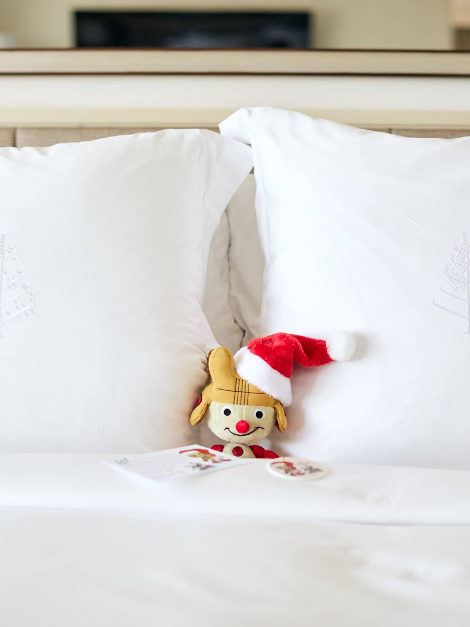A snow man plush in a bed with white sheets.