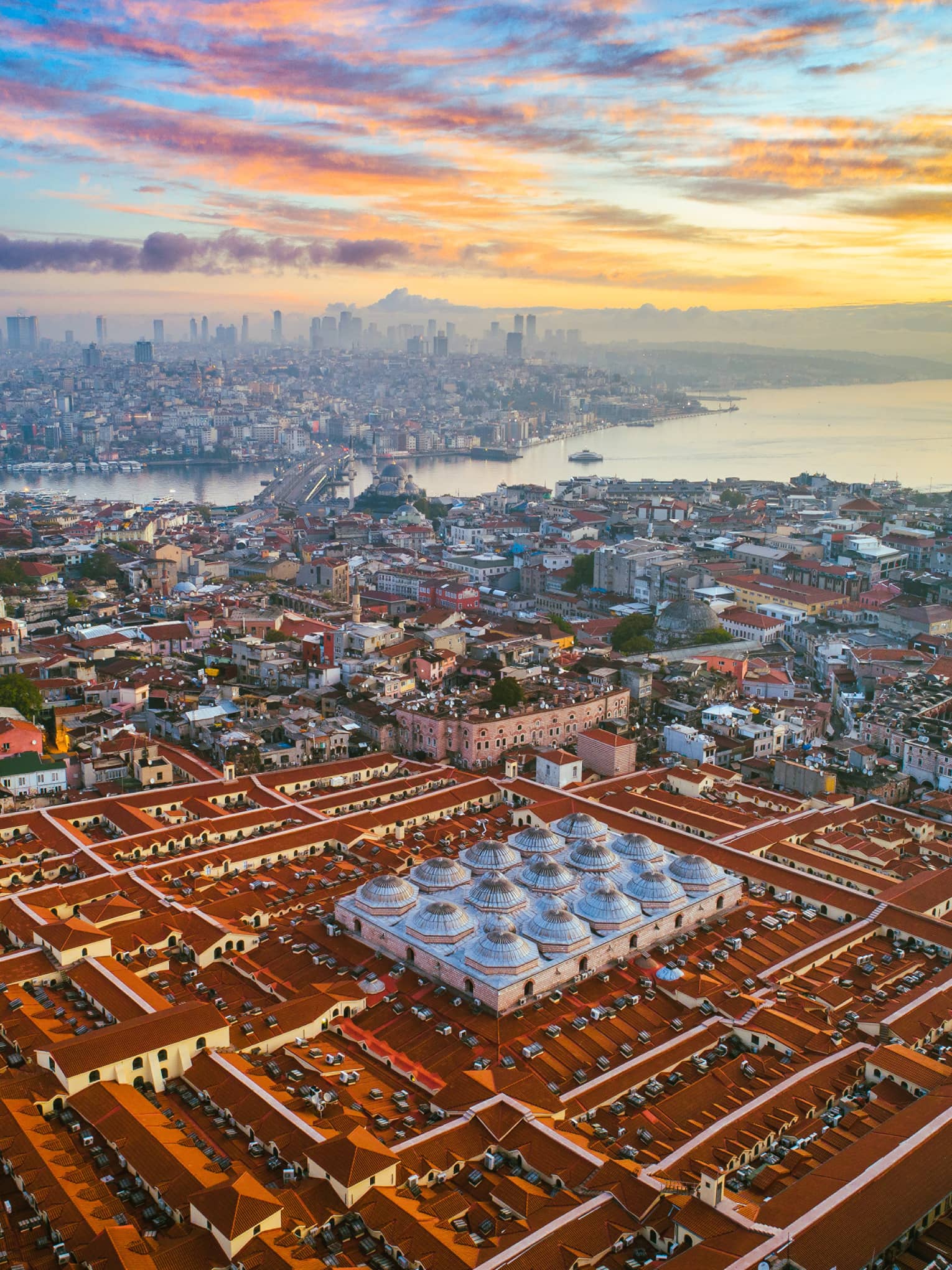 Aerial view of city rooftops, buildings and bridge at sunset