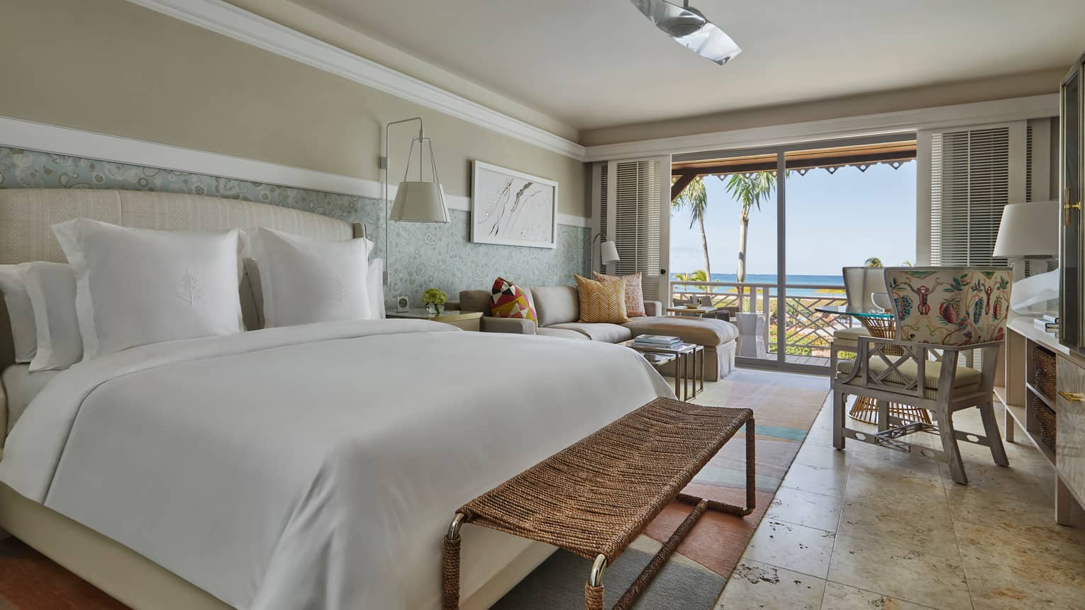 Light shines onto a large bed and marble tiled floors from the outdoor patio