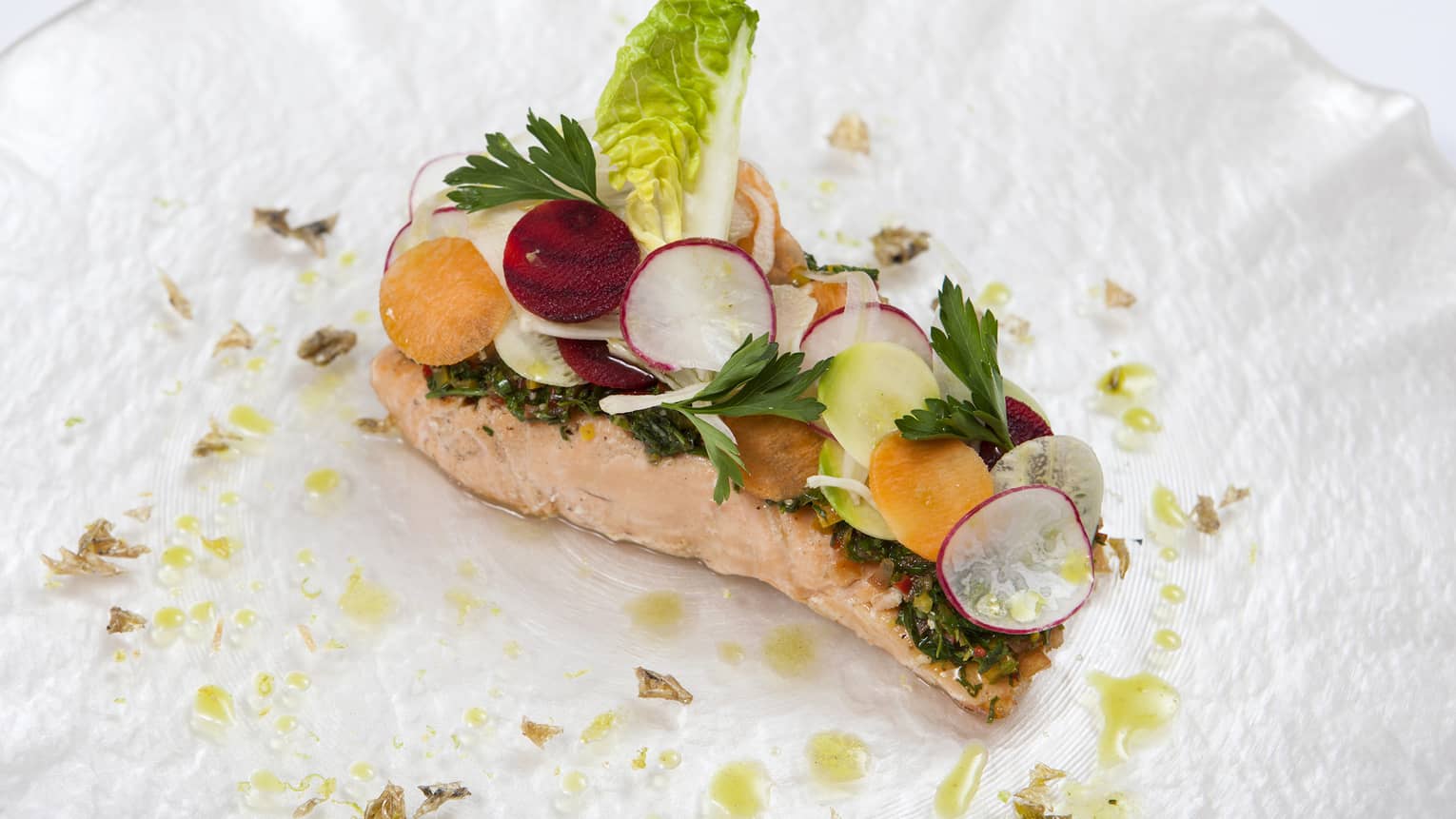 Seared salmon fillet topped with radish and lettuce garnish