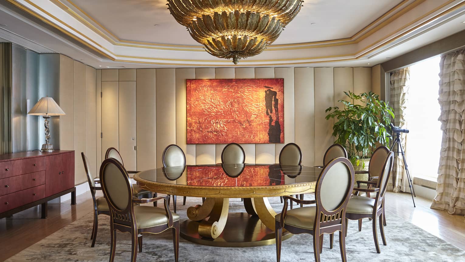 Elegant dining room with a round glass table, upholstered chairs, and a large red abstract painting on the wall. 