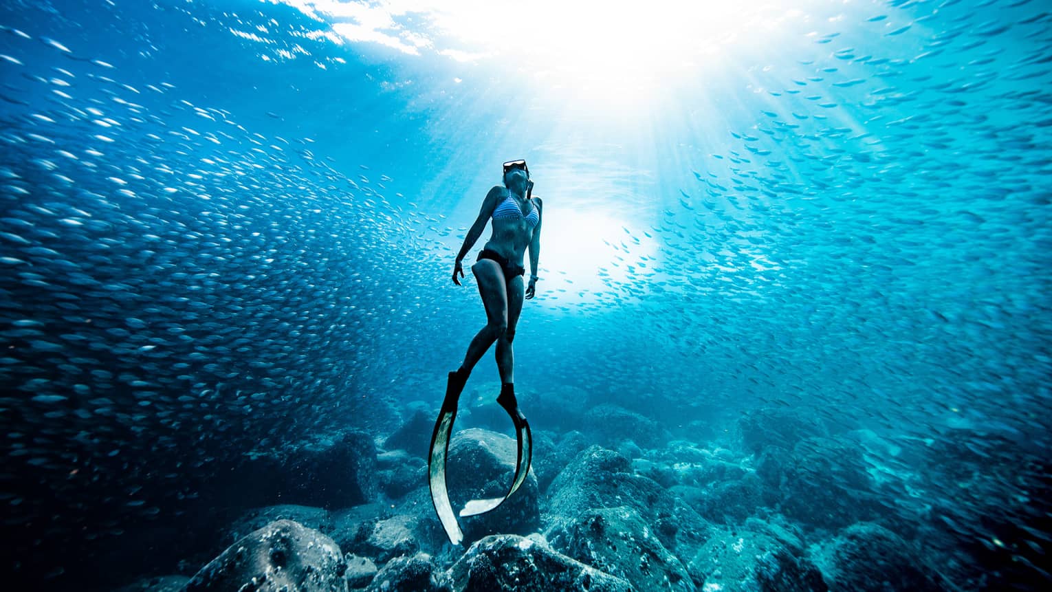 A woman in bikini wears scuba slippers below the surface of the ocean water