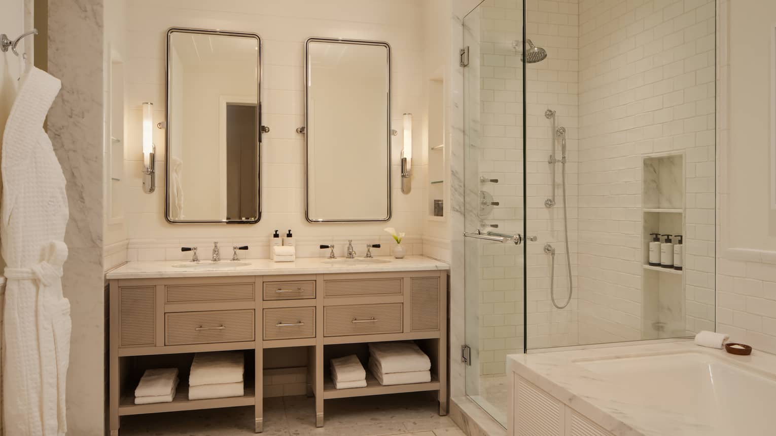 Luxury hotel bathroom with double vanity, two vertical mirrors, walk-in shower and separate marble bath tub