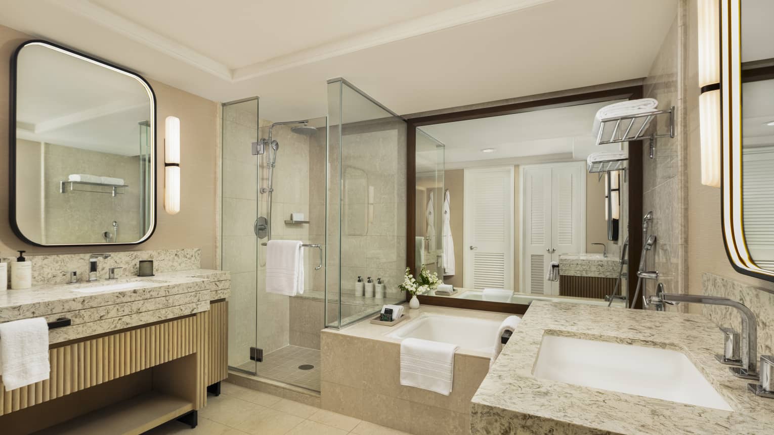 Hotel room bathroom featuring sunken tub, separate glass shower and a sink vanity on each side of the bathroom