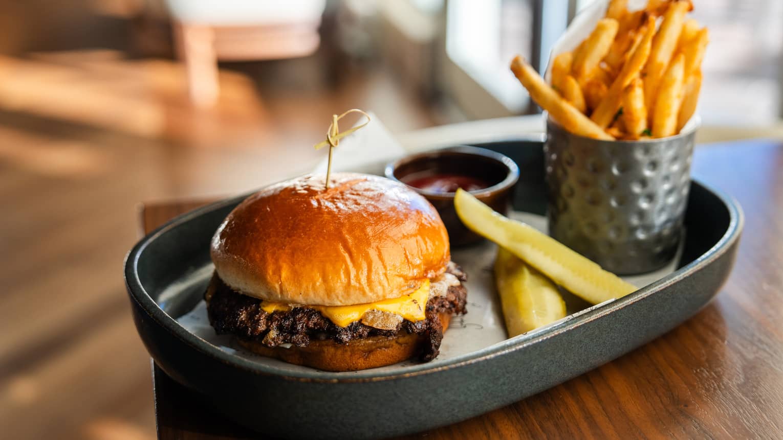 Cheeseburger and fries with two pickles and a side of ketchup
