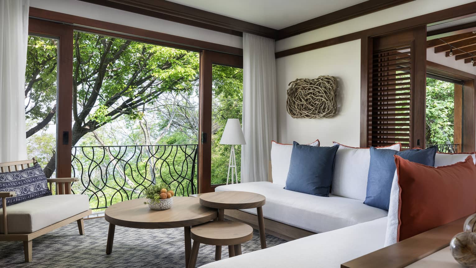Pacifico Two-Bedroom Resort Residence living room with white L-shaped sofa, three-tiered table by large open wall