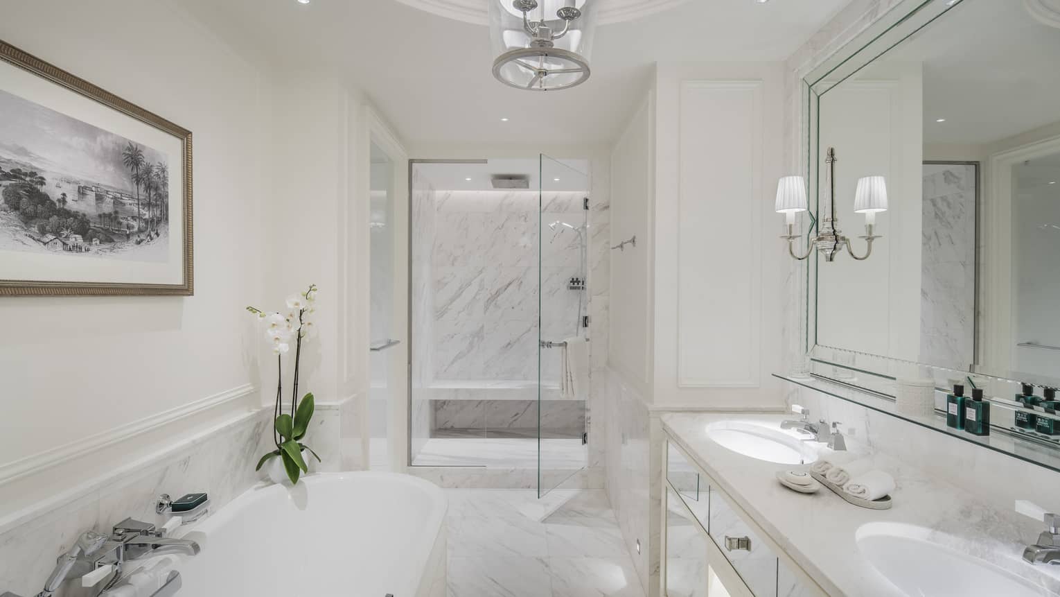 A marble bathroom with a large tub separate from a glass-walled shower.