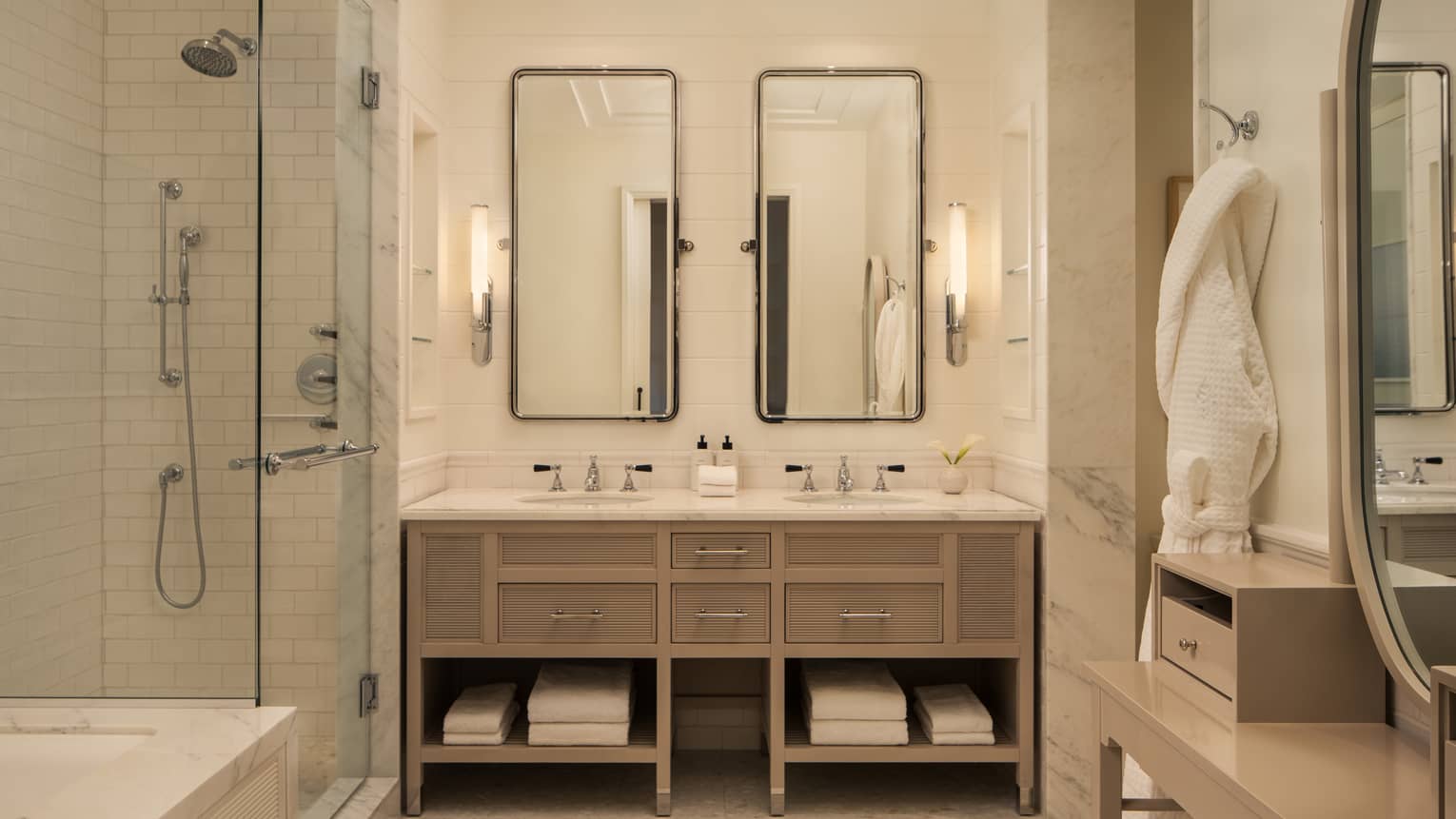 Luxury hotel bathroom with double vanity, glass-enclosed shower and bath tub