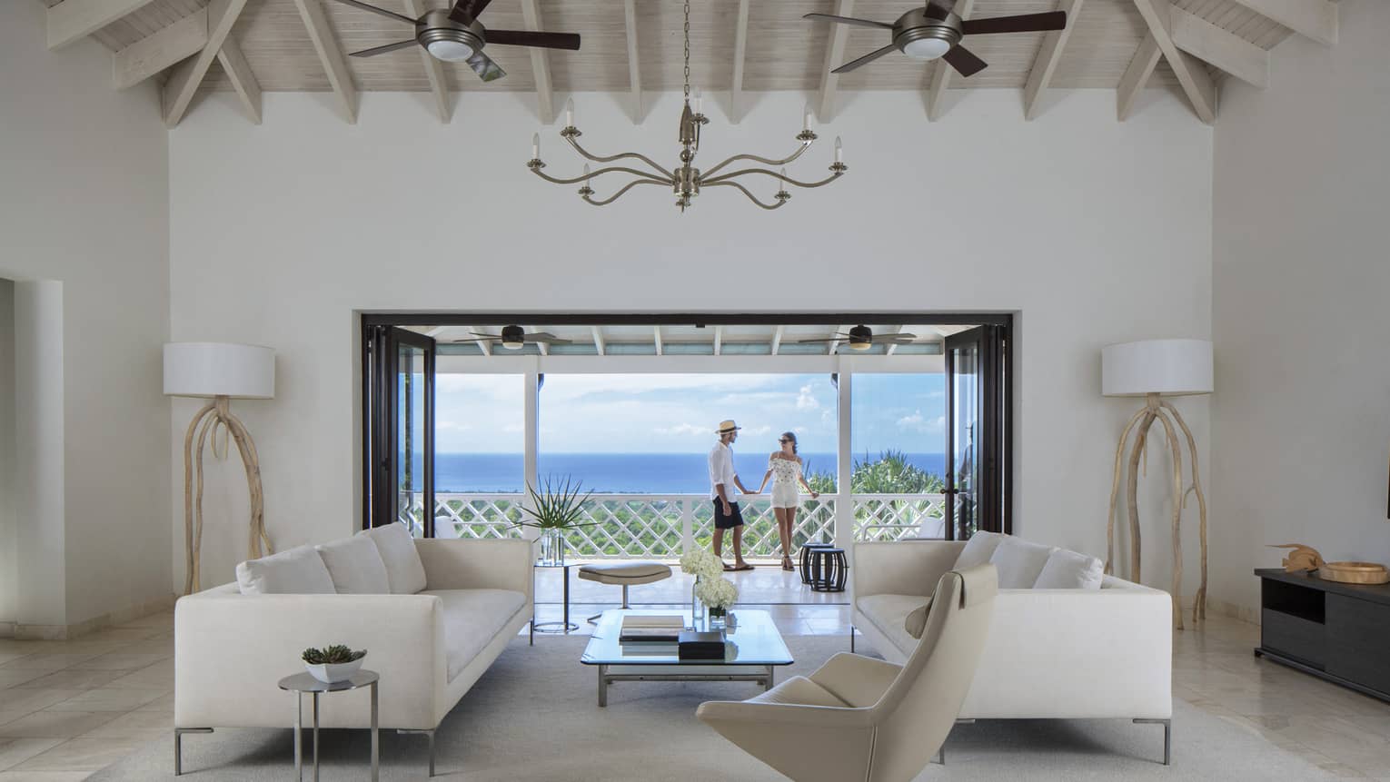 Living room with modern white furniture in front of open doors to sunny patio, couple