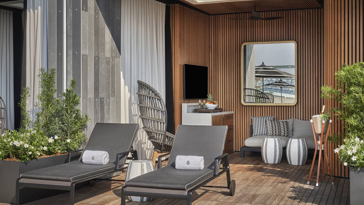 A cabana with two lounge chairs a sofa and plants.