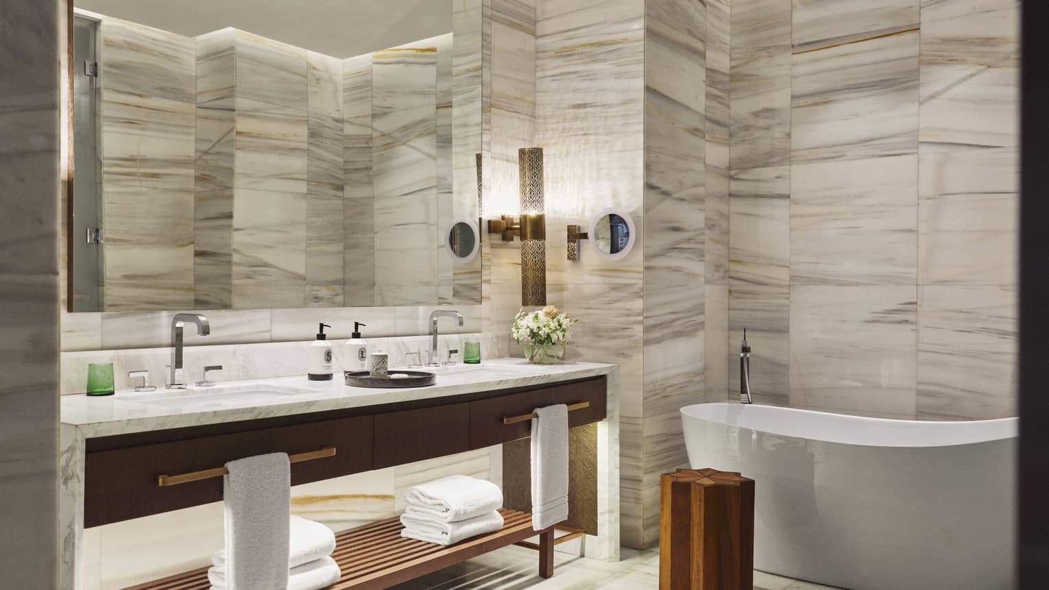 Hotel suite bathroom with marble walls and freestanding tub