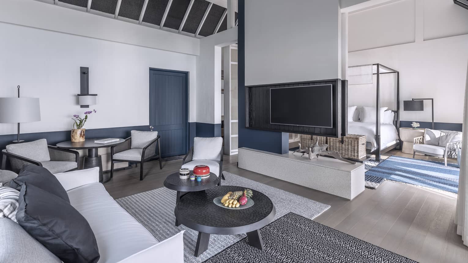 A brightly lit, cozy living room with a television, couch and access to the bedroom