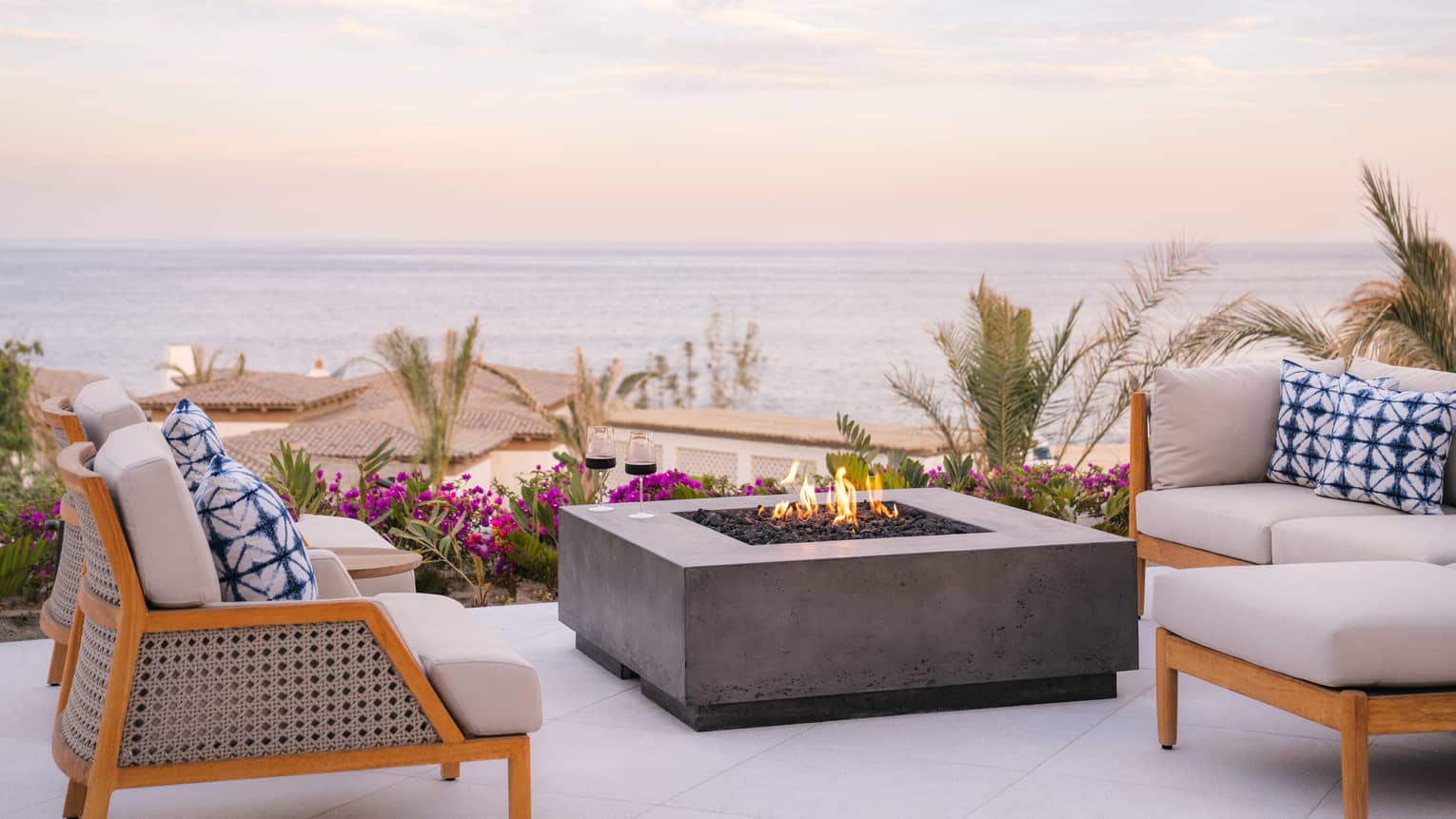 Outdoor lounge chairs and has firepit table and ocean view at luxury resort