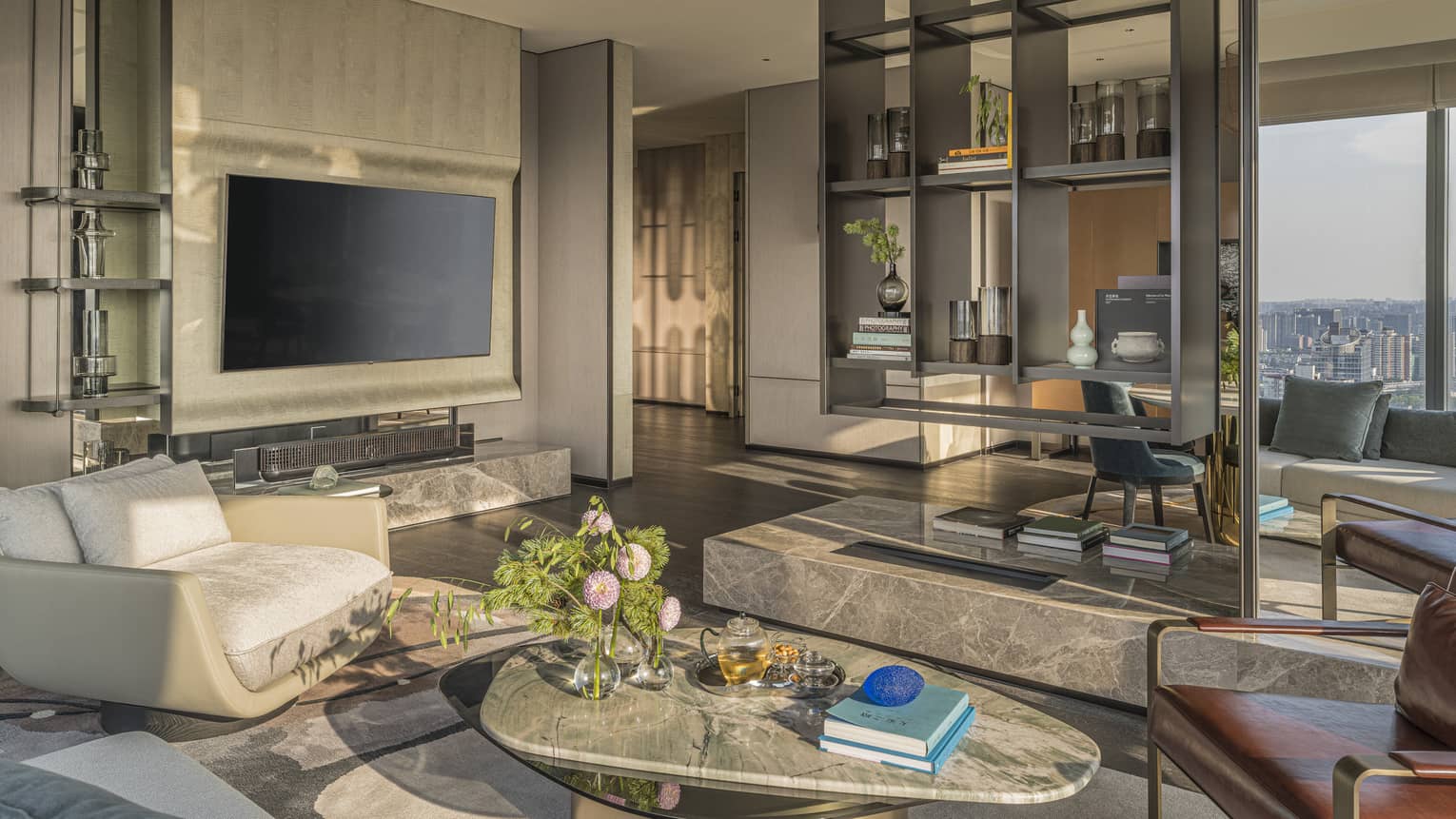 Stylish, large living room with arm chairs, coffee table, floating shelves and TV in Penthouse Suite at Four Seasons Hotel Hangzhou at Hangzhou Centre