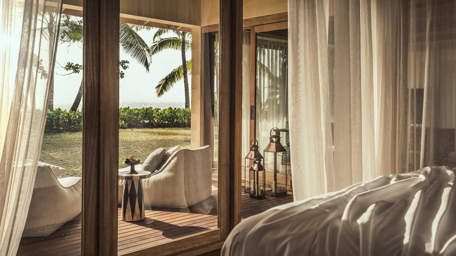 Desroches Suite bedroom floor-to-ceiling glass patio doors, cushioned chairs on deck