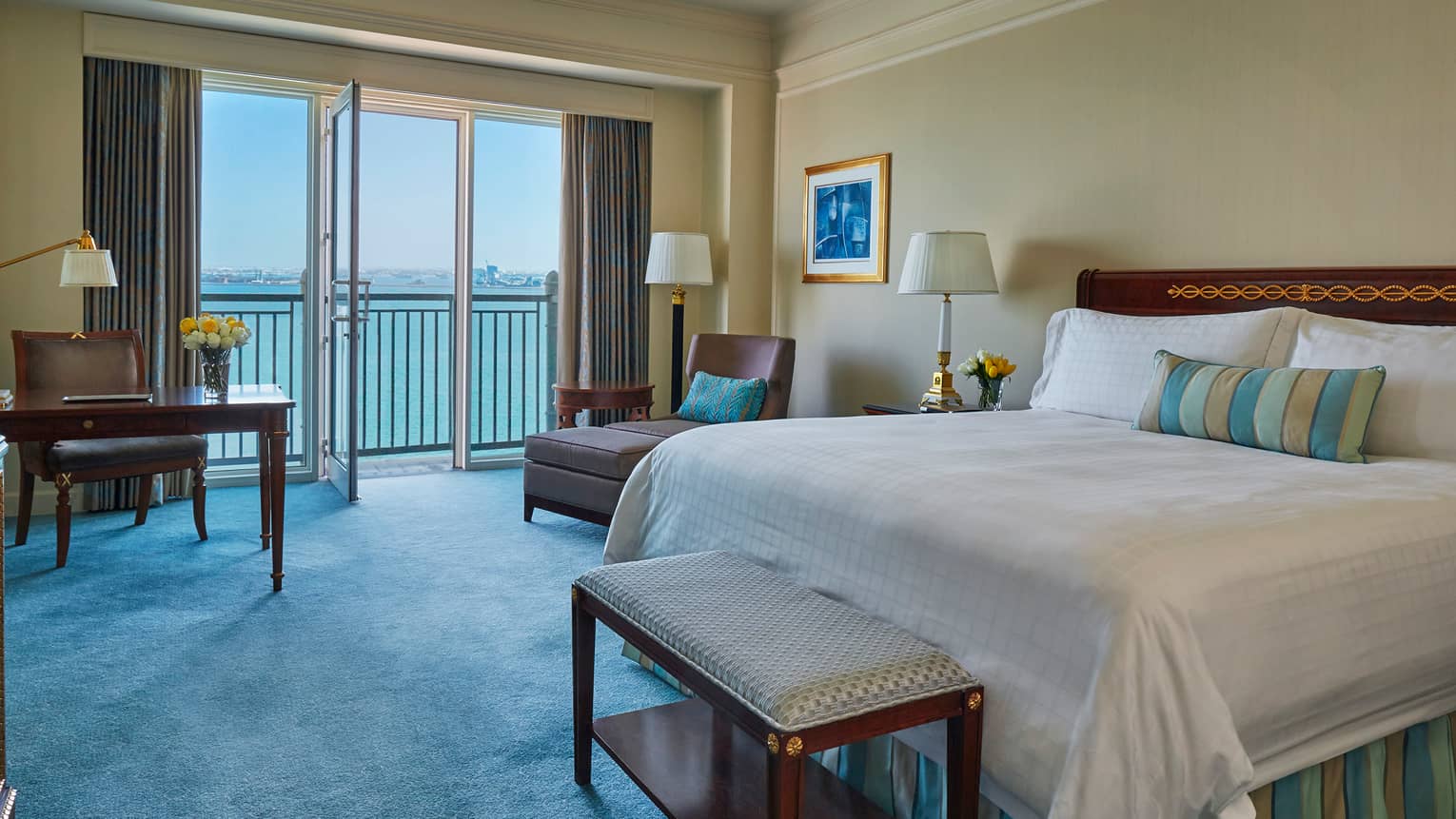 Premier Room with open glass balcony door, ocean view, blue carpet, bed with striped accent pillow