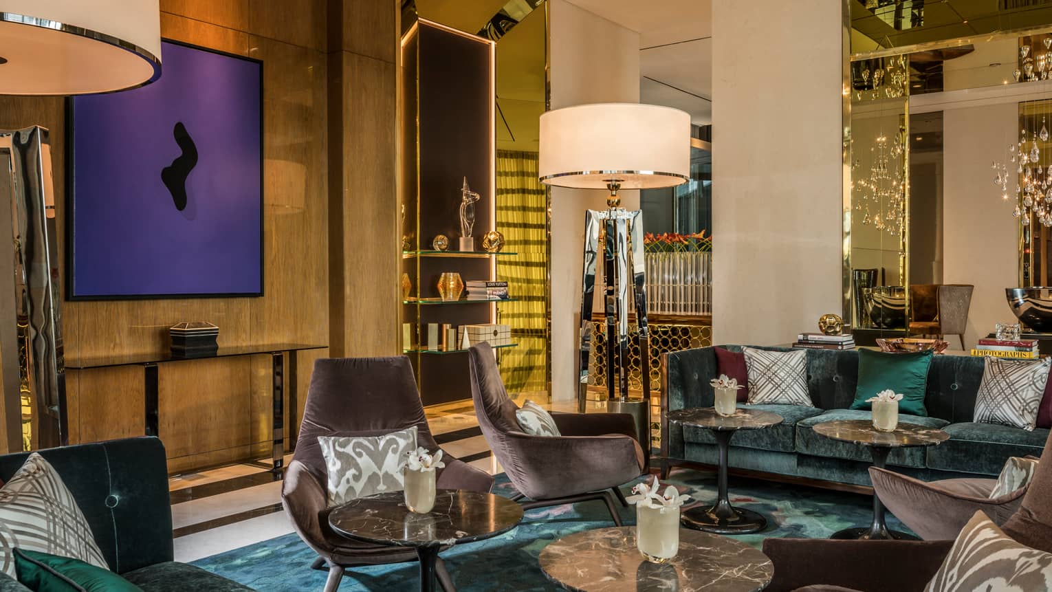 Penrose Lounge seating area with mid-century style velvet armchairs, accent pillows, tall lamps