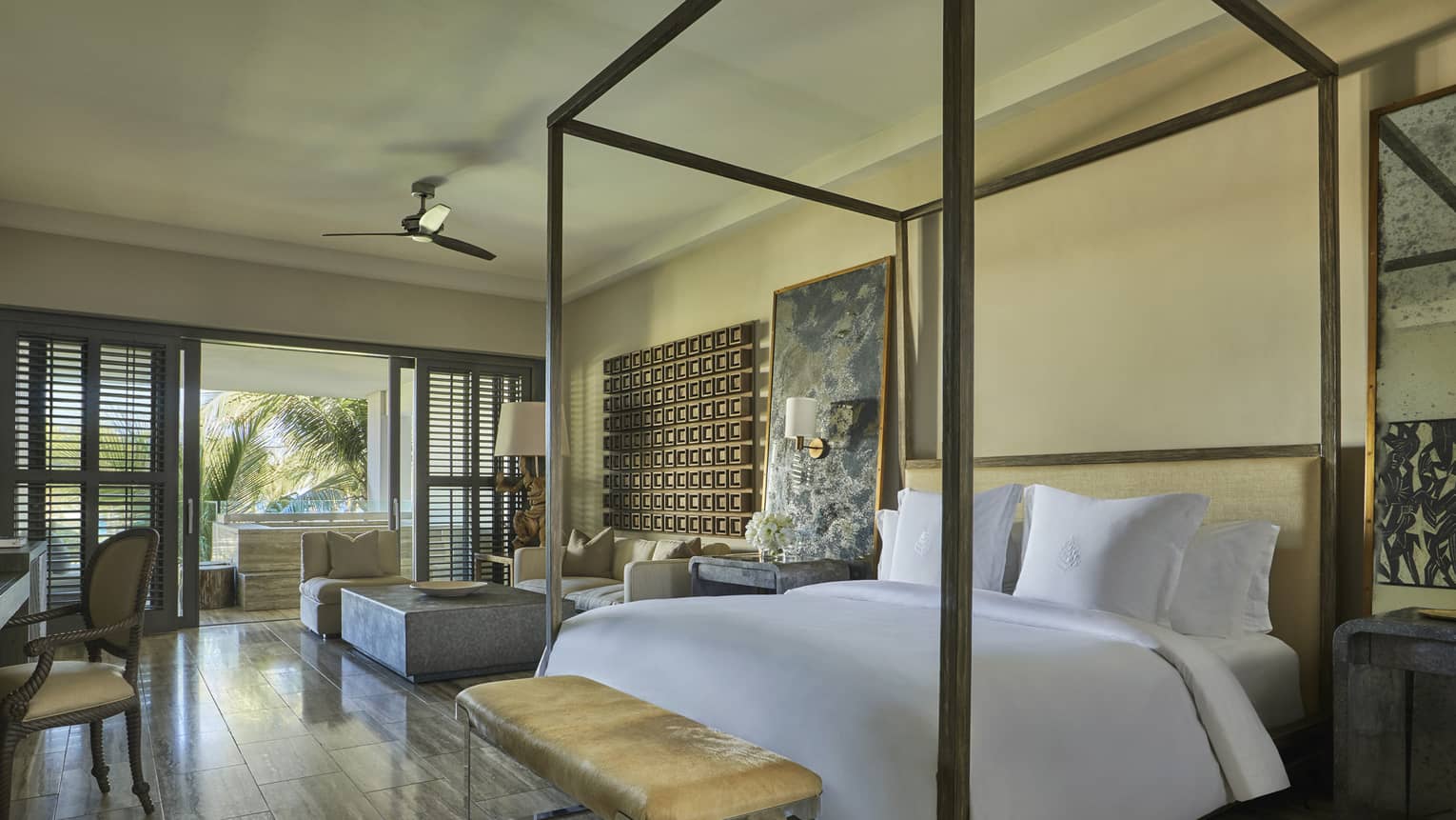 Deluxe Ocean-View Studio Room bed with canopy frame, small brown leather bench, desk, patio doors with wood shutters