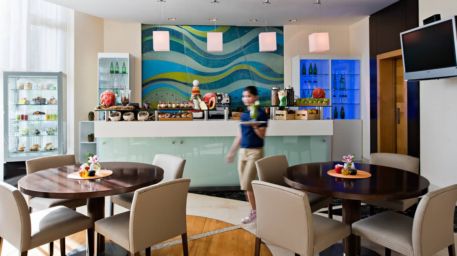 Server walks past dessert counter in bright Après Spa Café dining room