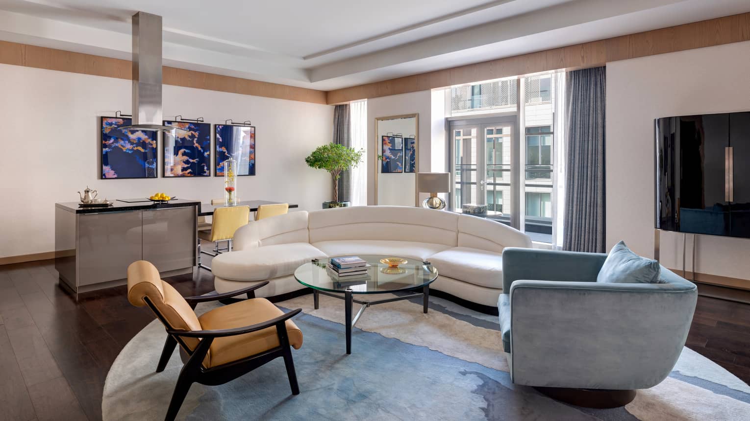 Living room with white curved sofa, blue arm chair, leather chair, dining area