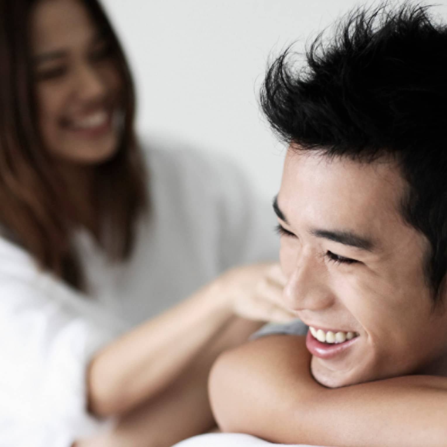 Smiling man rests chin on arms, woman in background