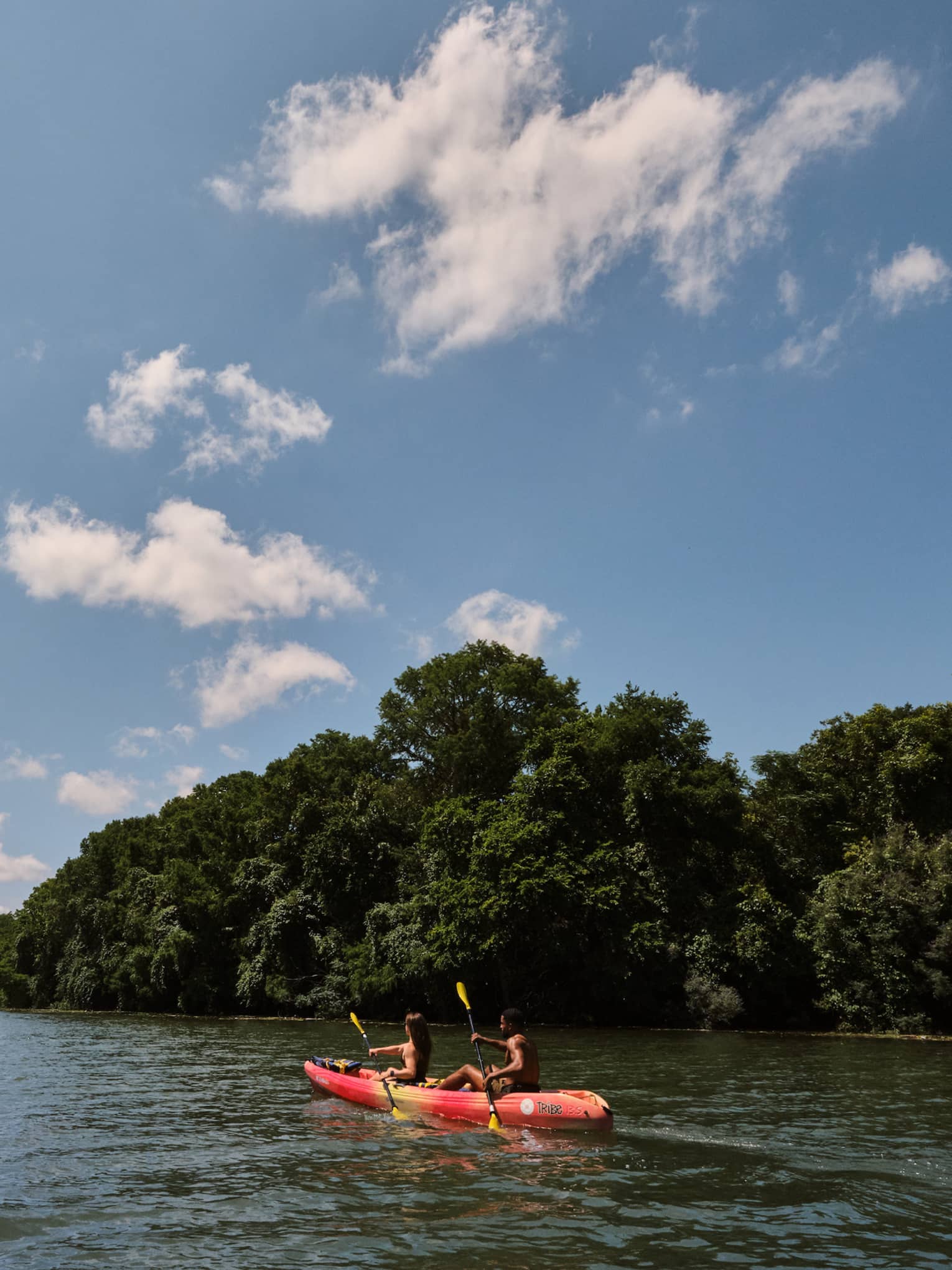 Two guests on a kayak using oars to move the kayak through the water