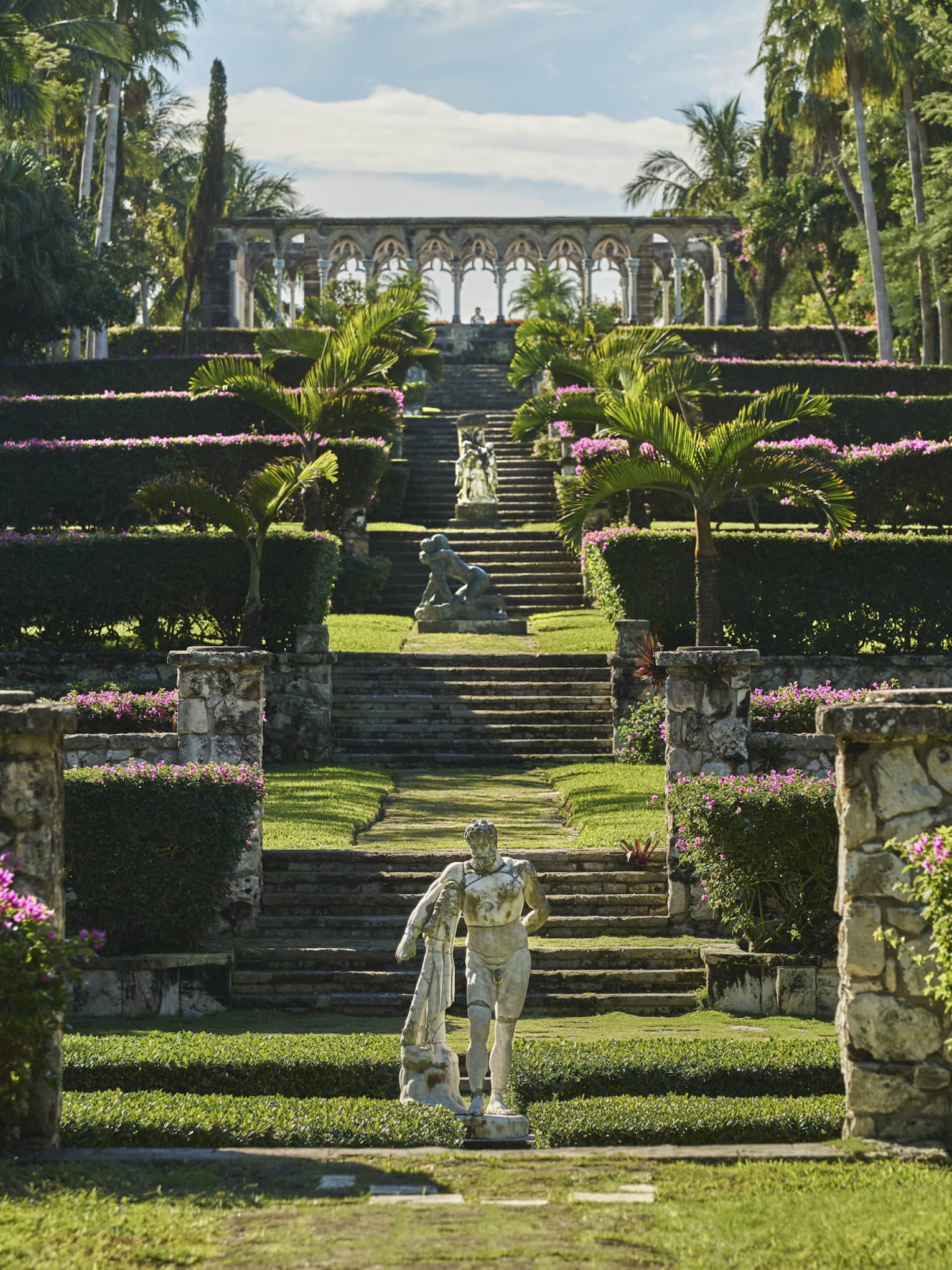 Garden with a staircase, pink flowers and a statue.