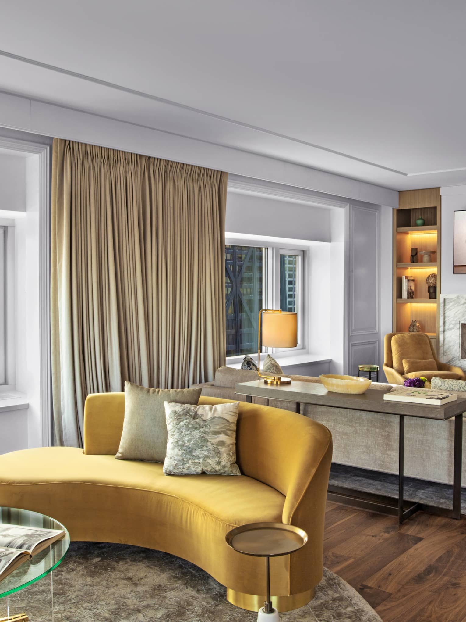 Suite with a yellow couch and glass table, as well as a television and fireplace.