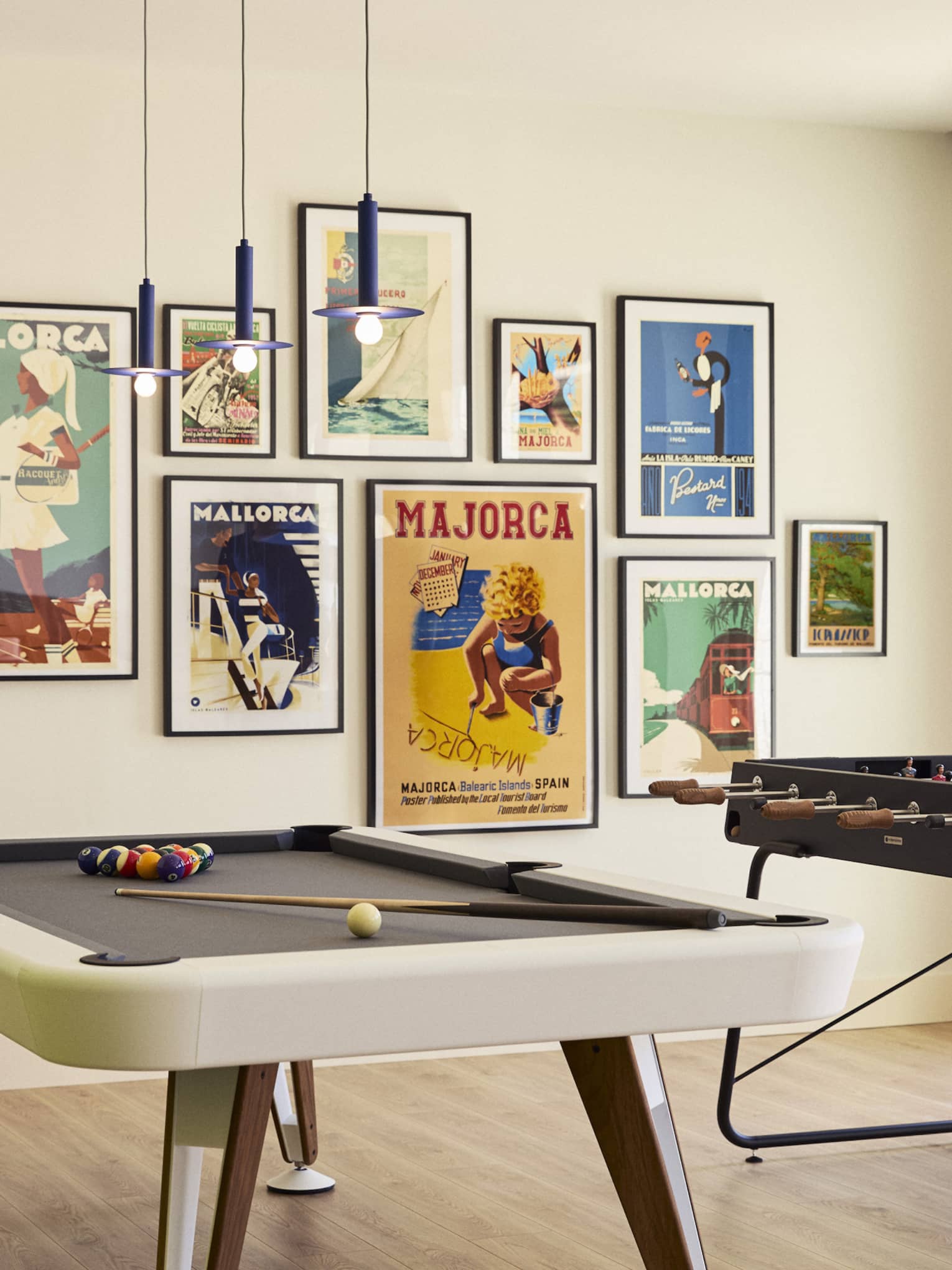 Game room with pool table and foosball table, and a wall of colourful retro prints