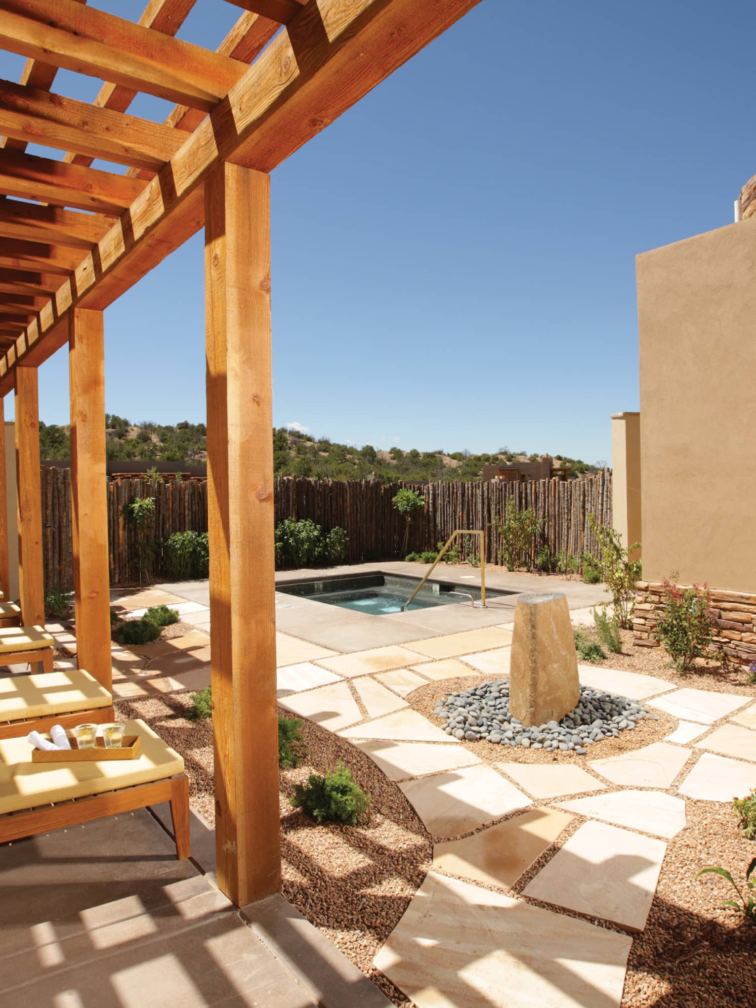 Shaded lounge chairs overlooking a stone patio spa area with a jacuzzi