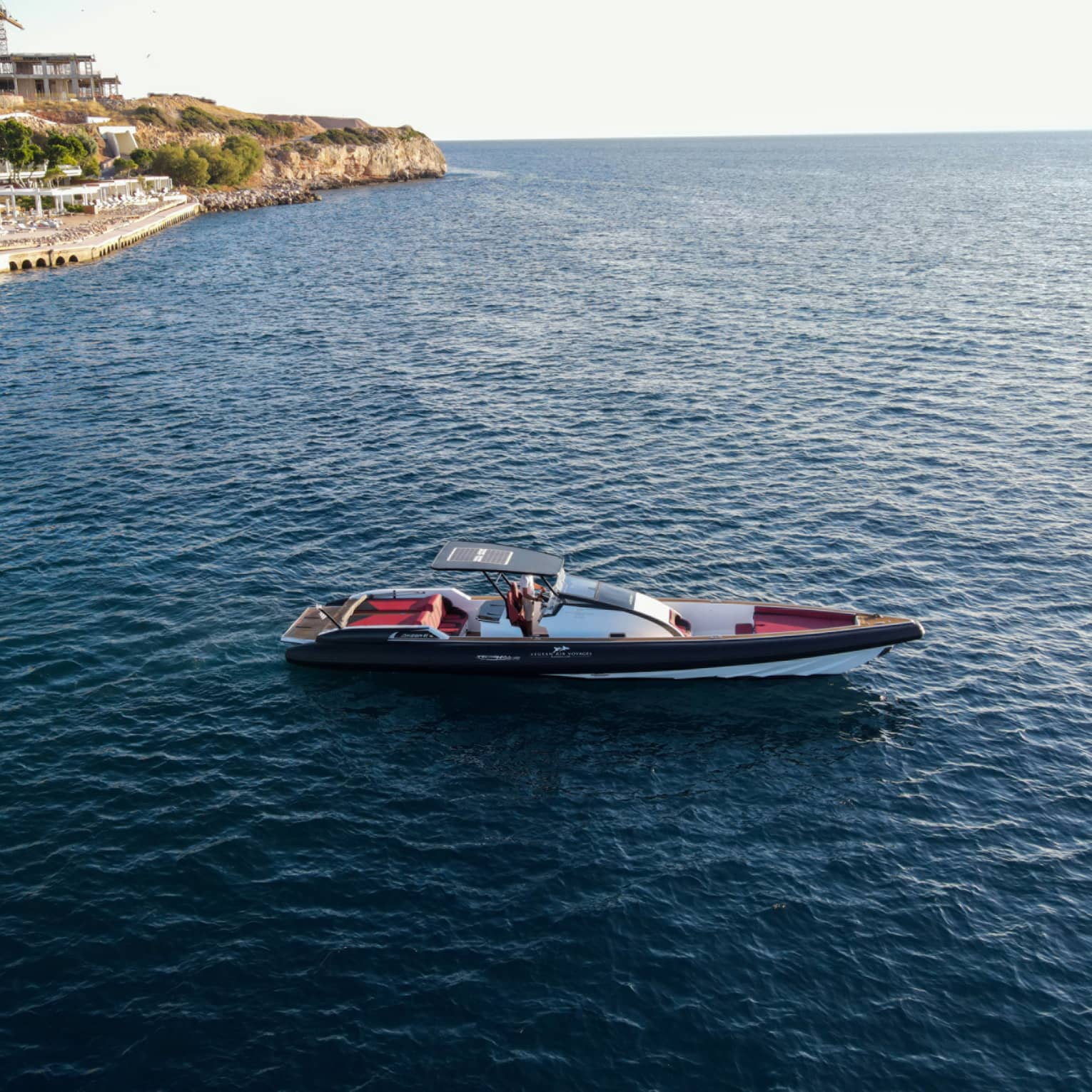 Small Greek-style yacht heading out toward open water from Astir Palace Hotel dock.