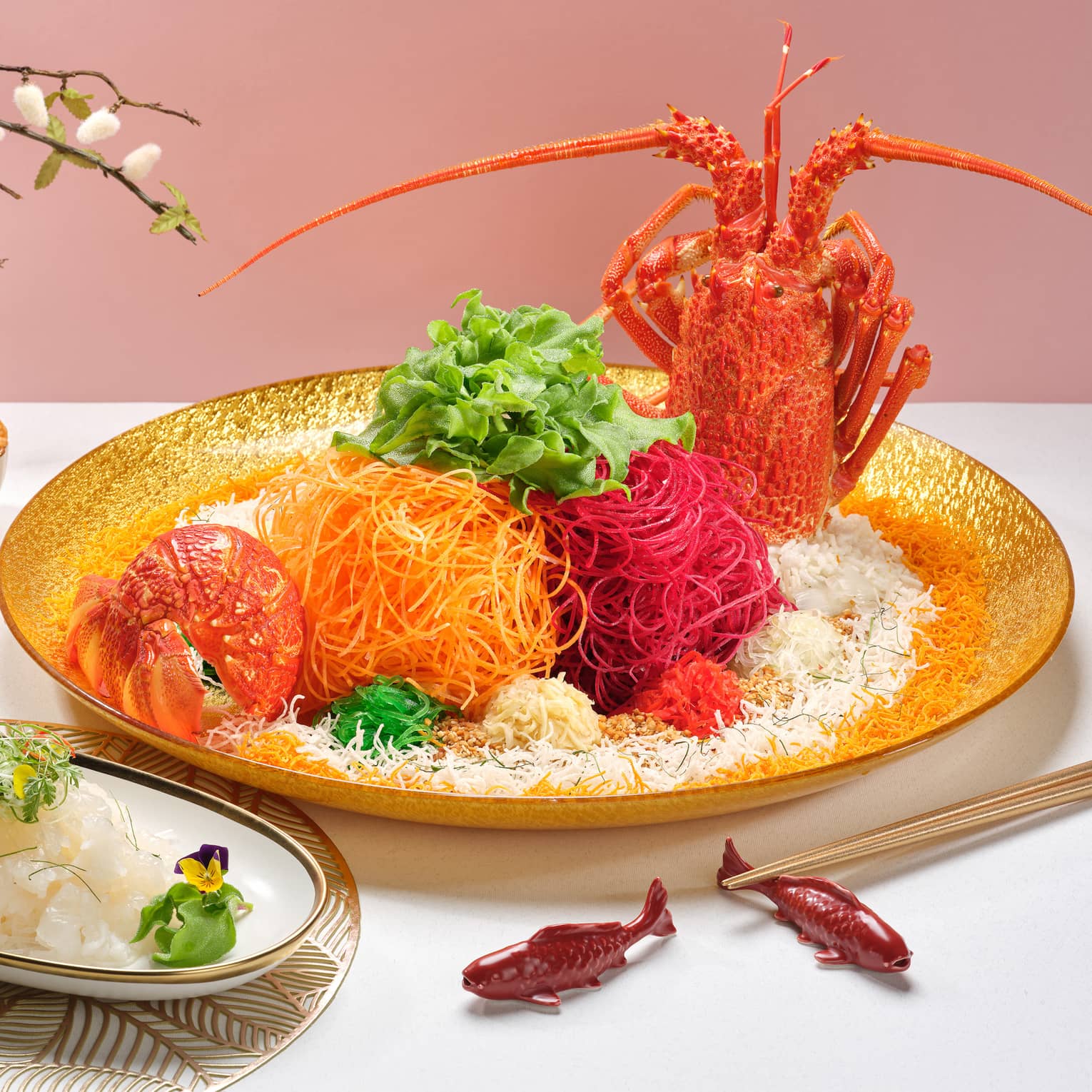 Colourful traditional Lunar New Year dish with whole lobster, shredded carrots and beets, dipping sauces and edible flowers