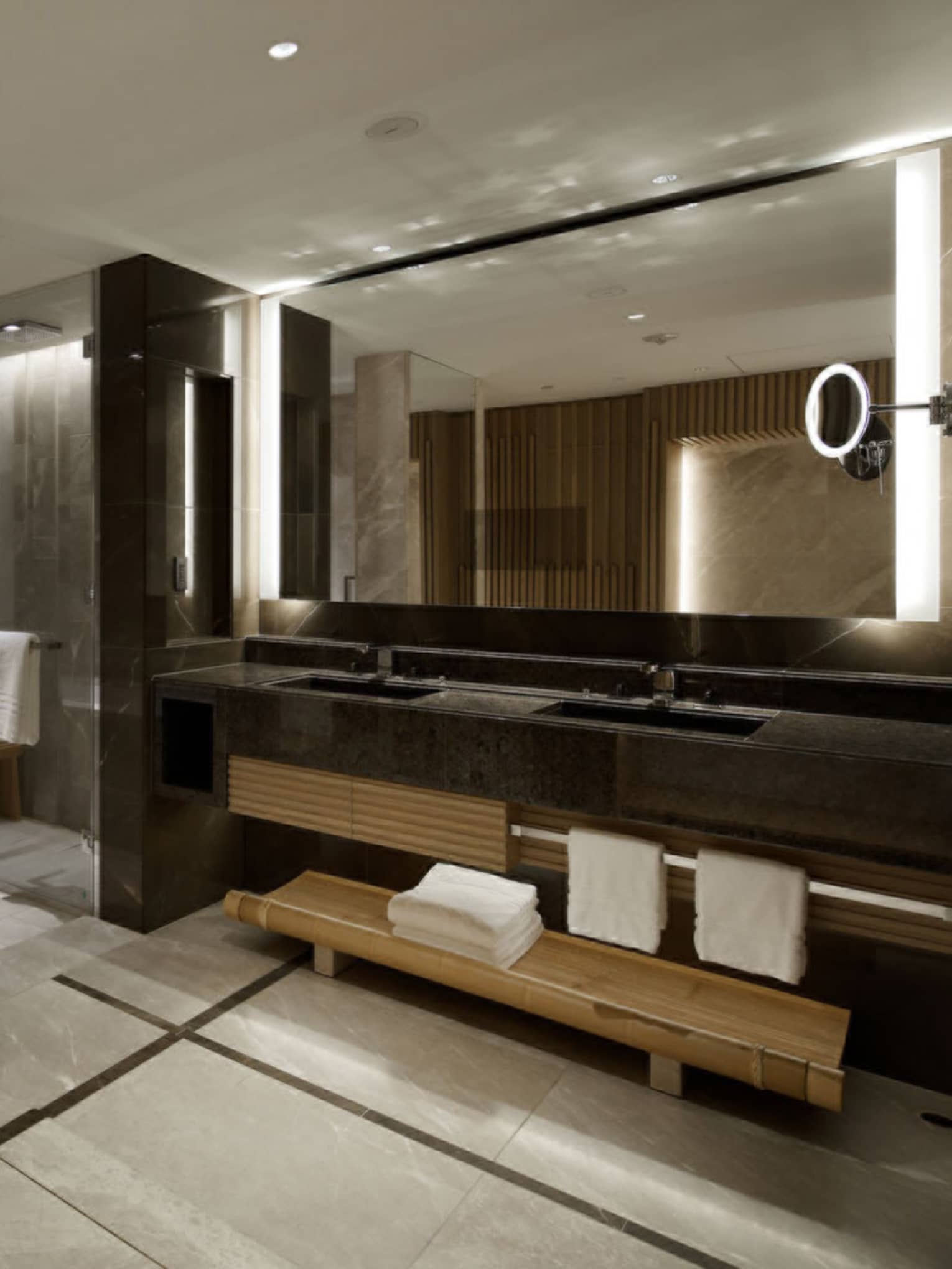 Spacious bathroom with a double-sink vanity, large mirrors and marble wall accents, connecting to the bedroom