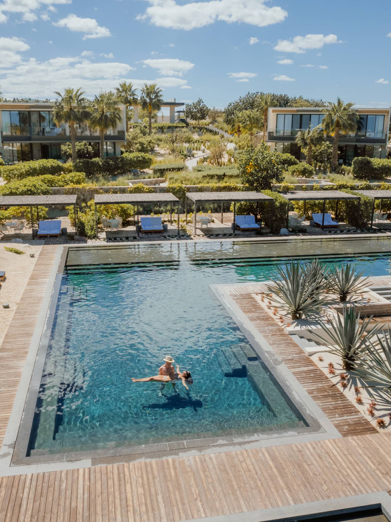 A couple stands in a large resort pool