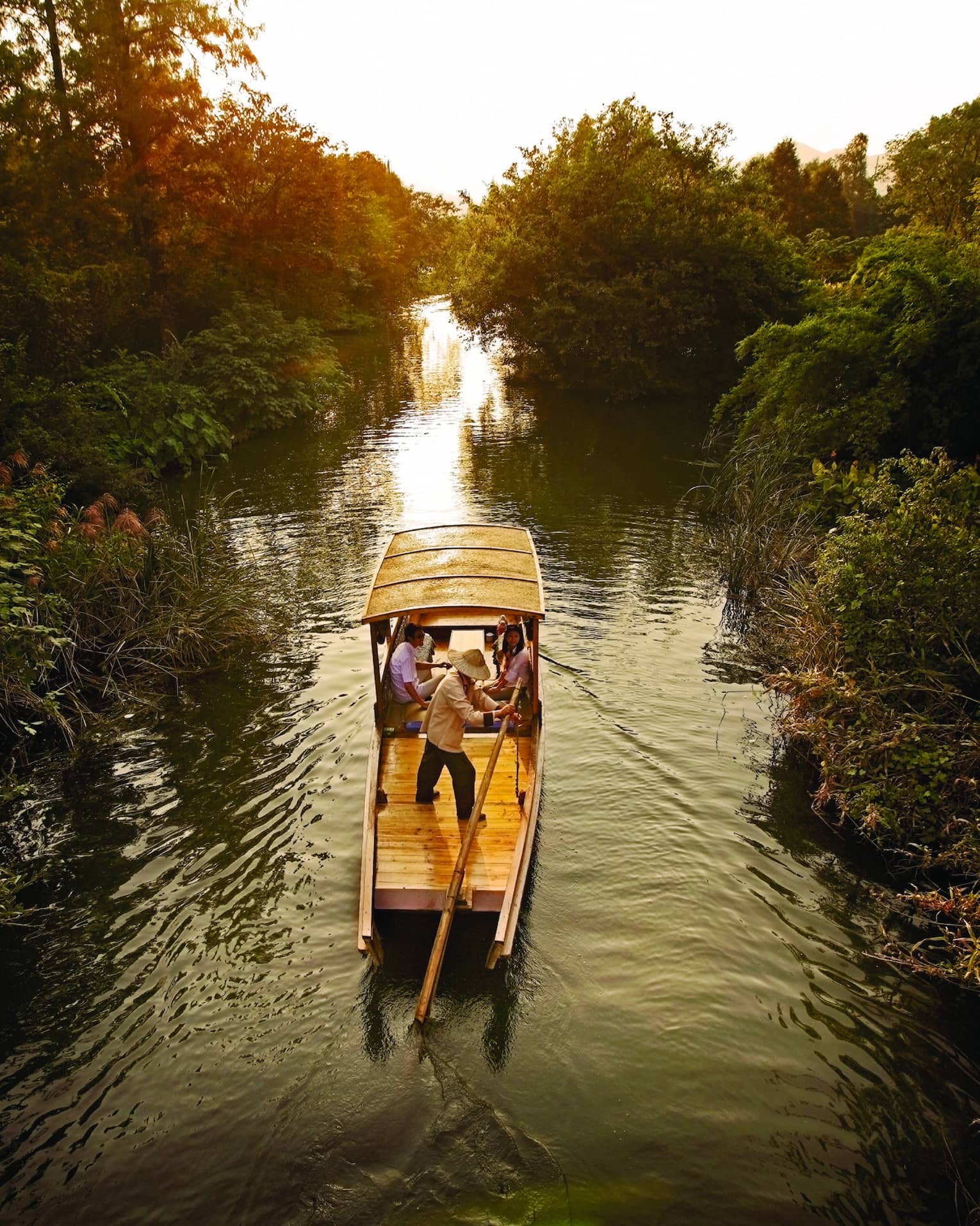 Traditional Chinese wooden boat sails down river in Xixi Wetland National Park