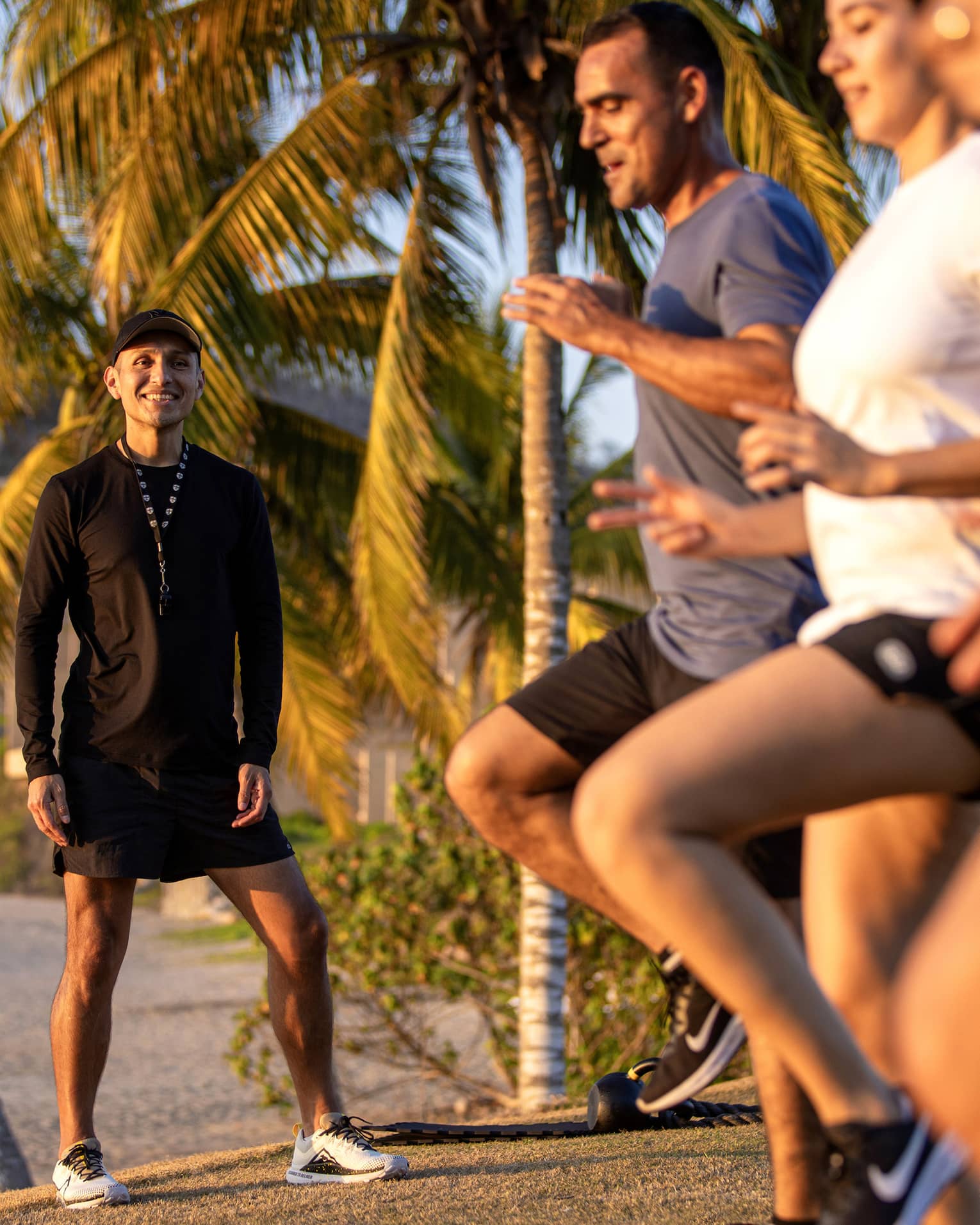 Fitness instructor leading an outdoor workout class with three guests.