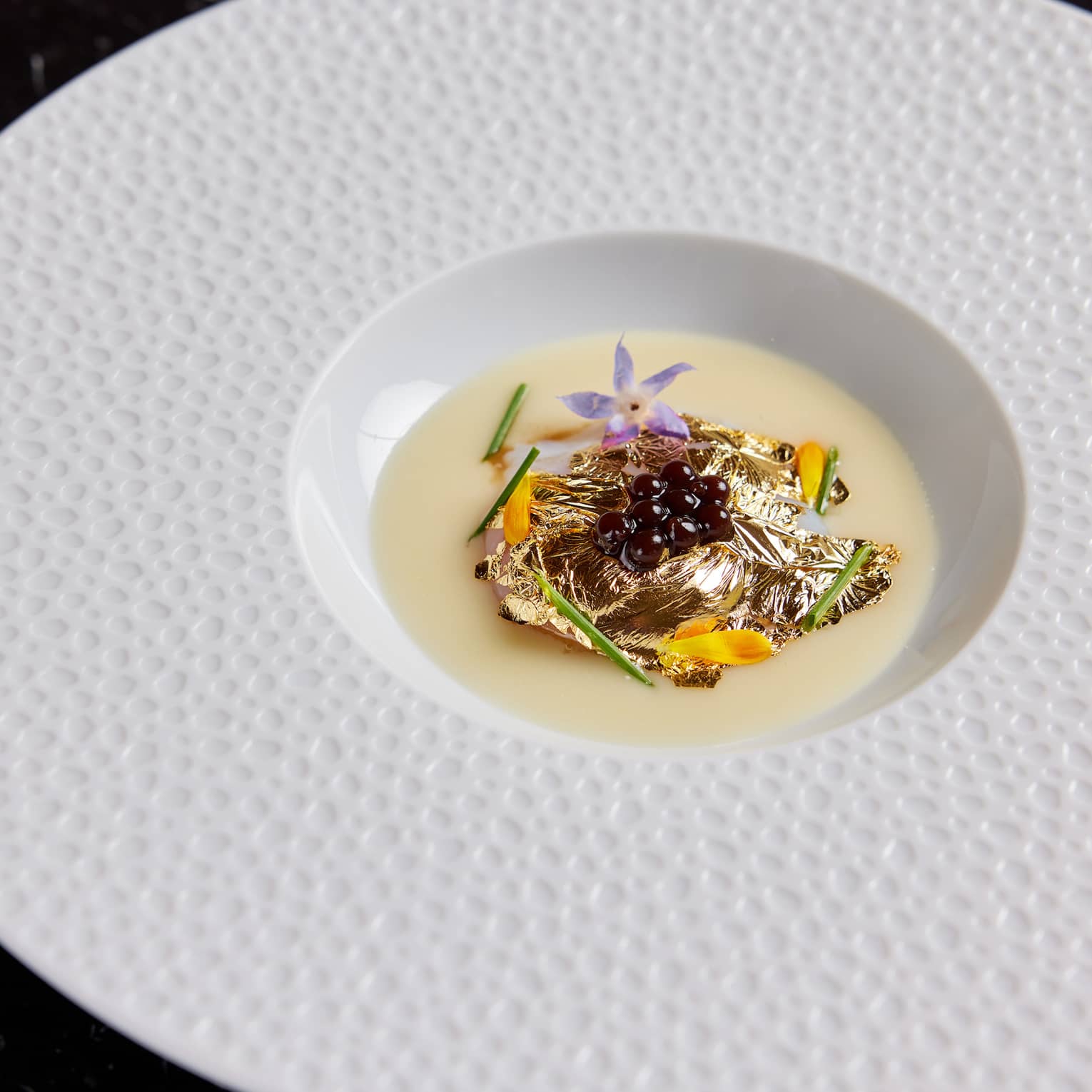 Food on a white plate on a dark table.