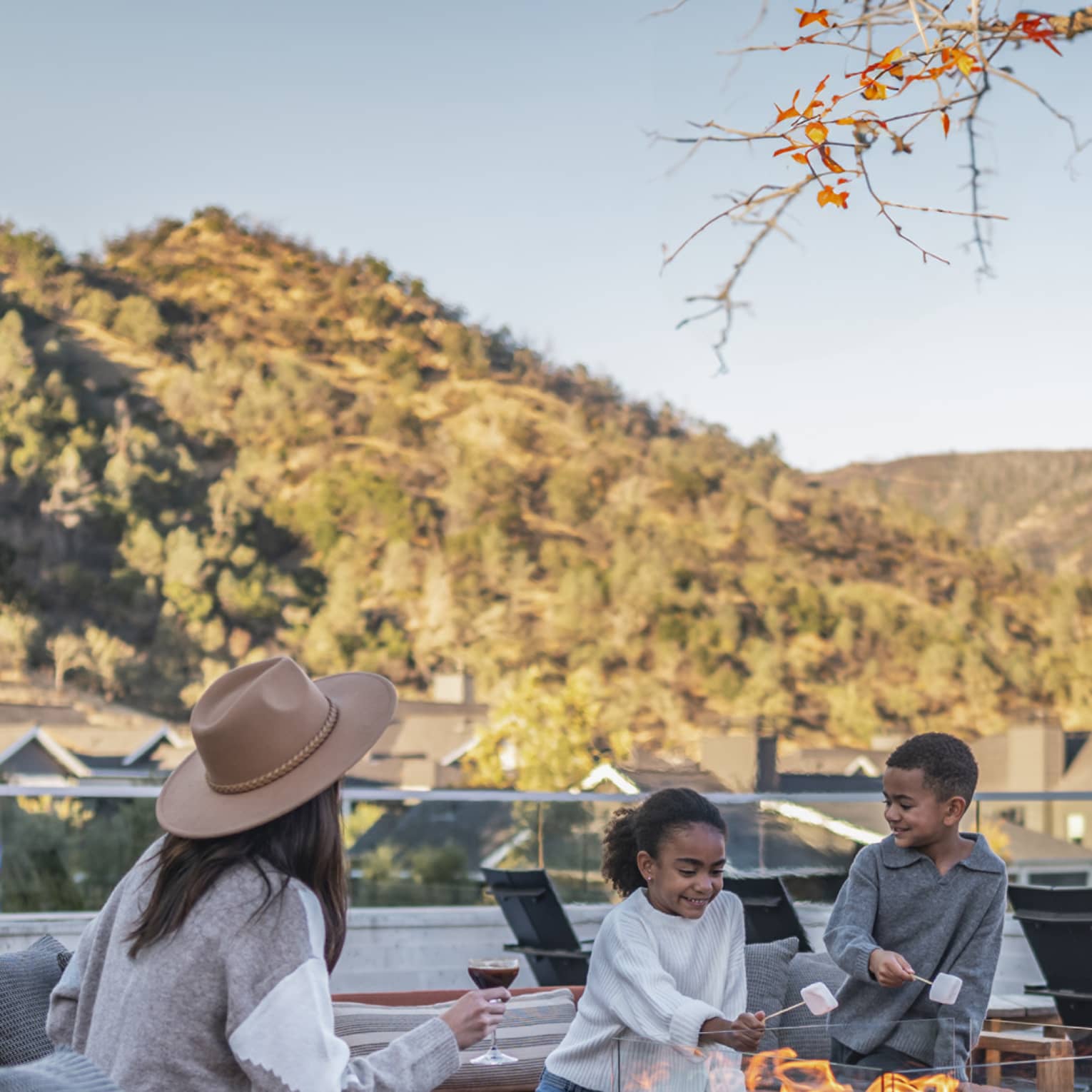 Three guests roasting marshmallows on an outdoor terrace.