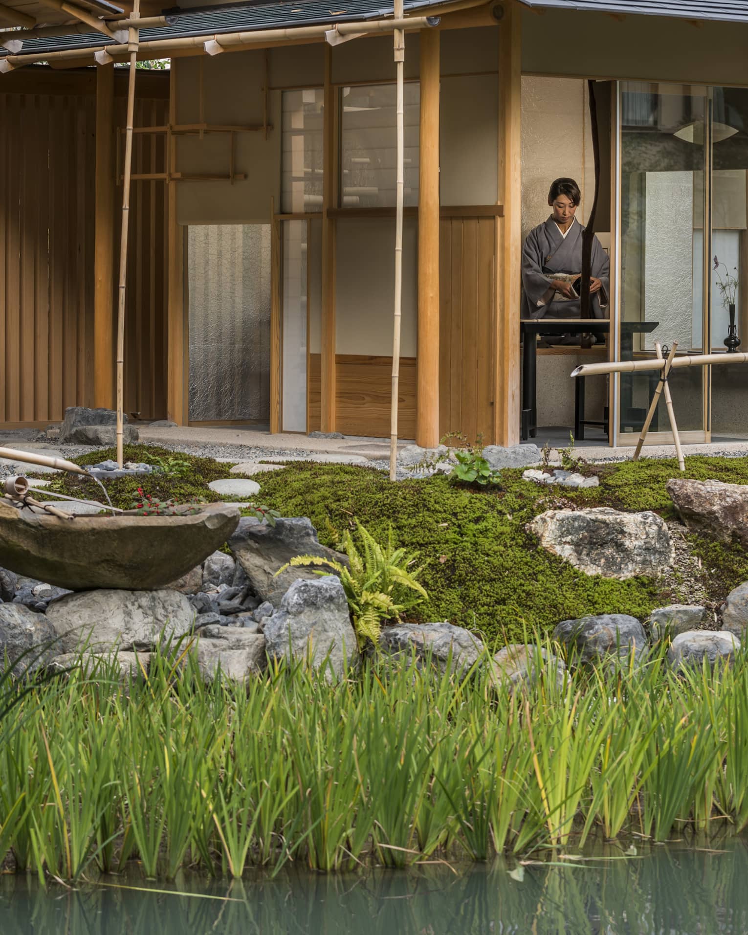 Rock garden, fountain in front of Shakusui tei building, woman in robe behind window