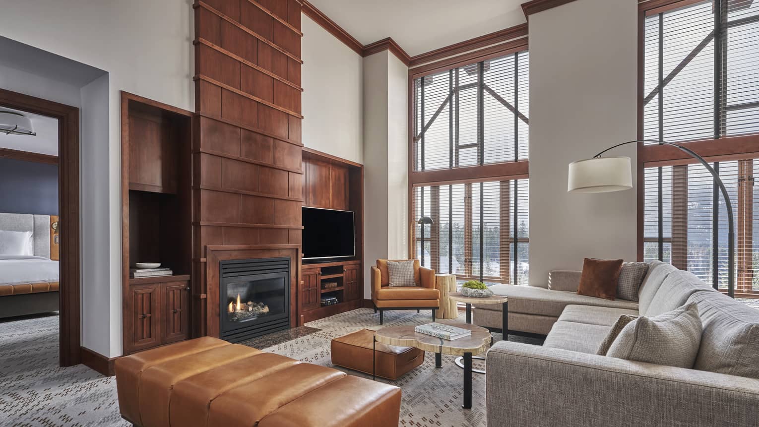 High-ceilinged living room of a suite, complete with a fireplace and light grey sofa