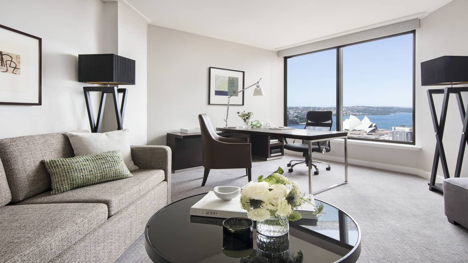 One Bedroom Full Harbour living area with grey sofa, round coffee table, writing desk, views of the Sydney Opera House