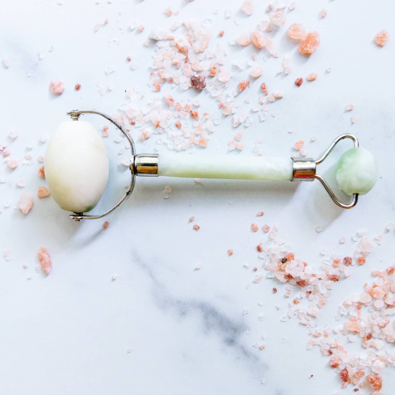 a spa roller tool on a white marble counter surrounded by himalayan salt