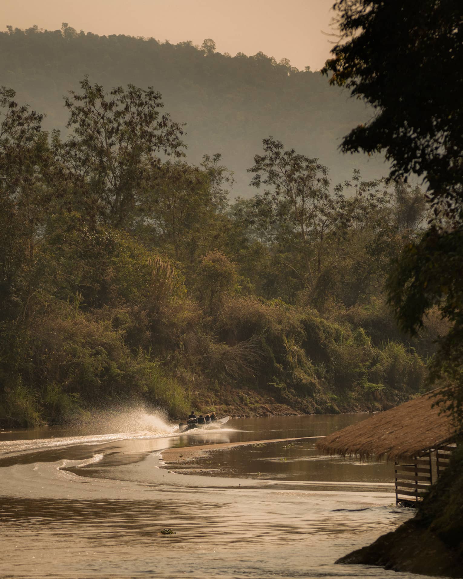 Longtail boat sprays water as it zips down the Ruak river