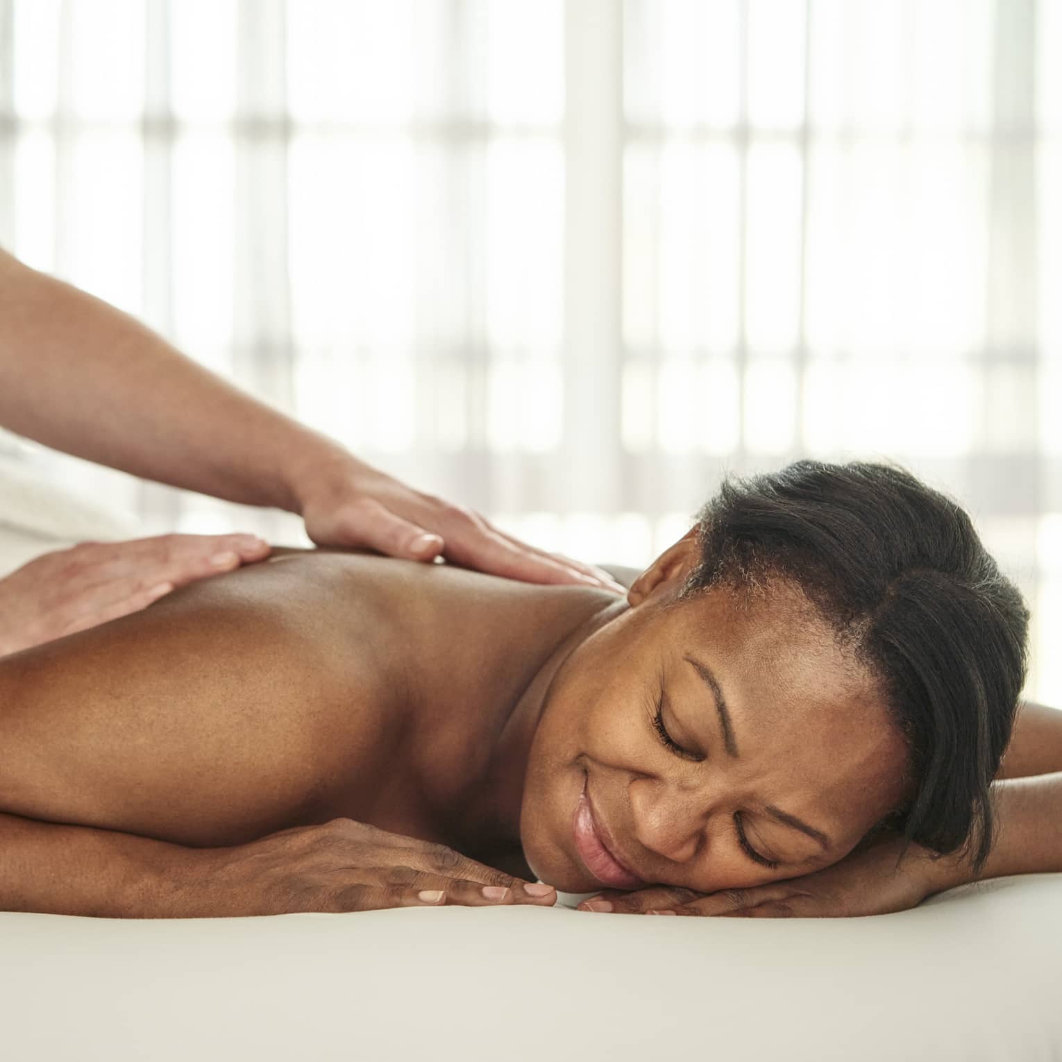 A person getting a massage in a well lit treatment room.