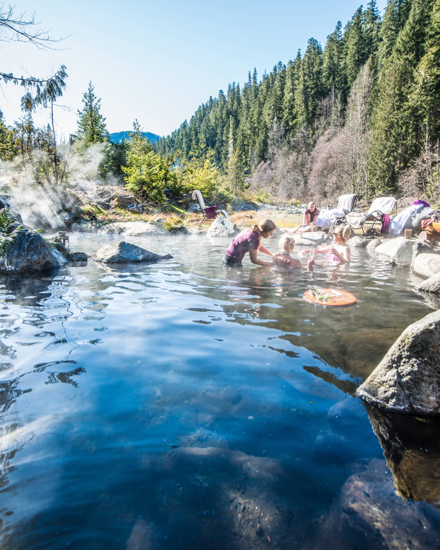 Group relaxes in hot springs, surrounded by forest 