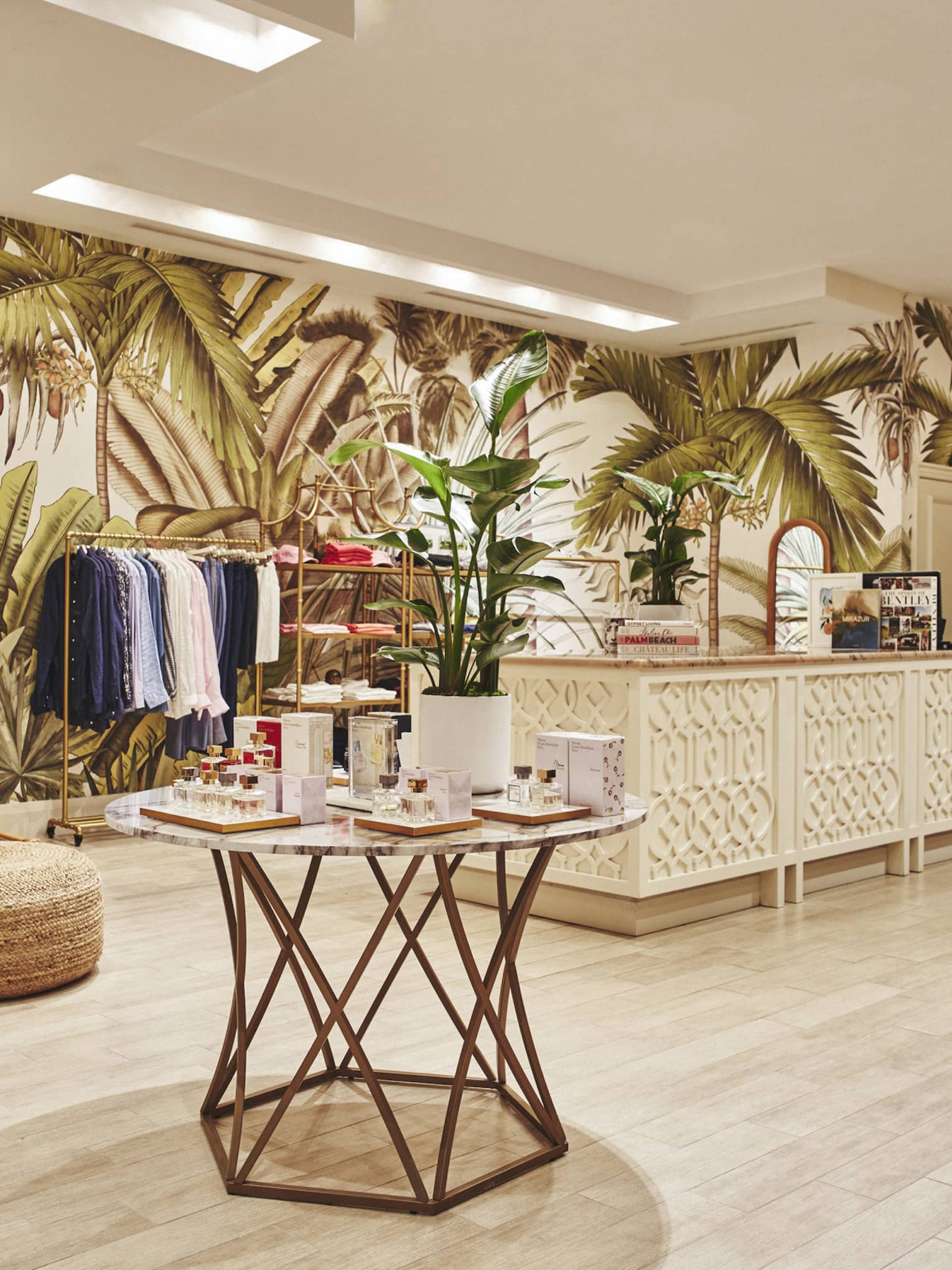 A brightly lit store with light wood features and clothes on shelves and hangers.