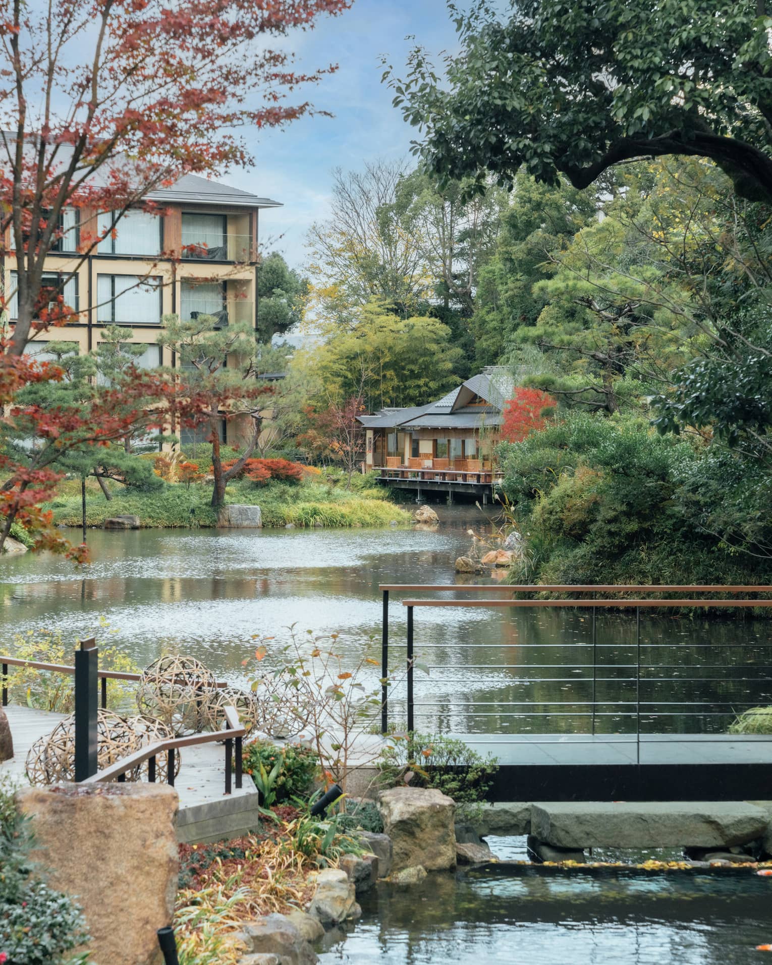 A pond surrounded by trees and crossed by a foot bridge