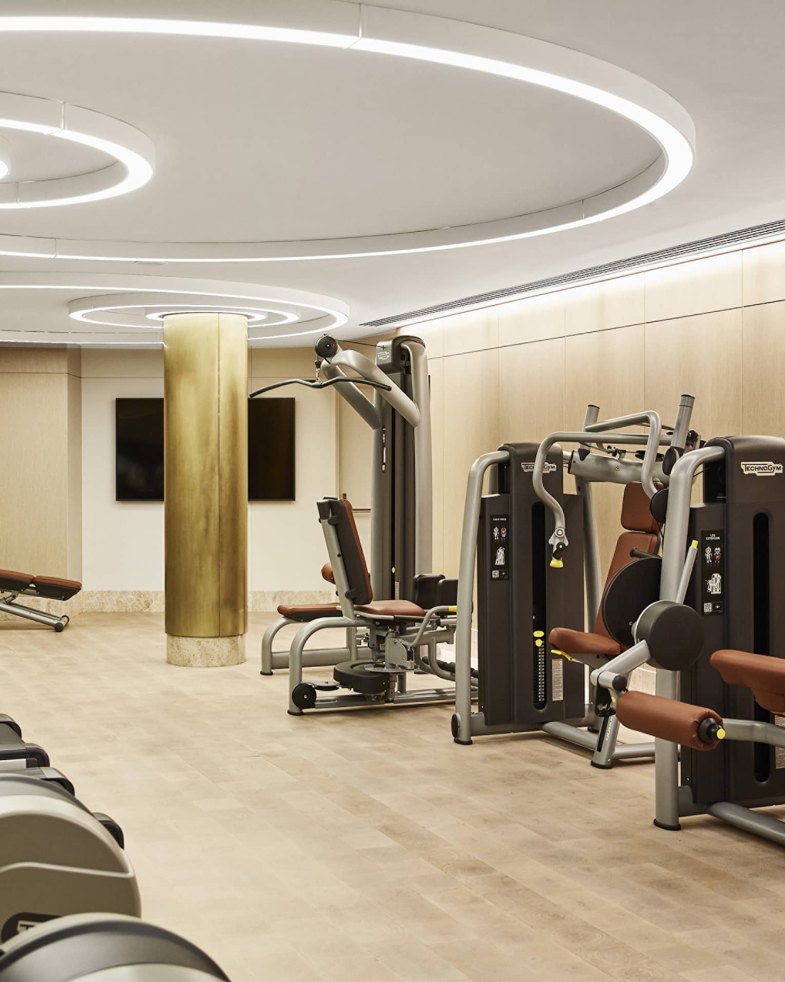 Fitness centre with three treadmills, weight-training machines, modern circular lights on the ceiling