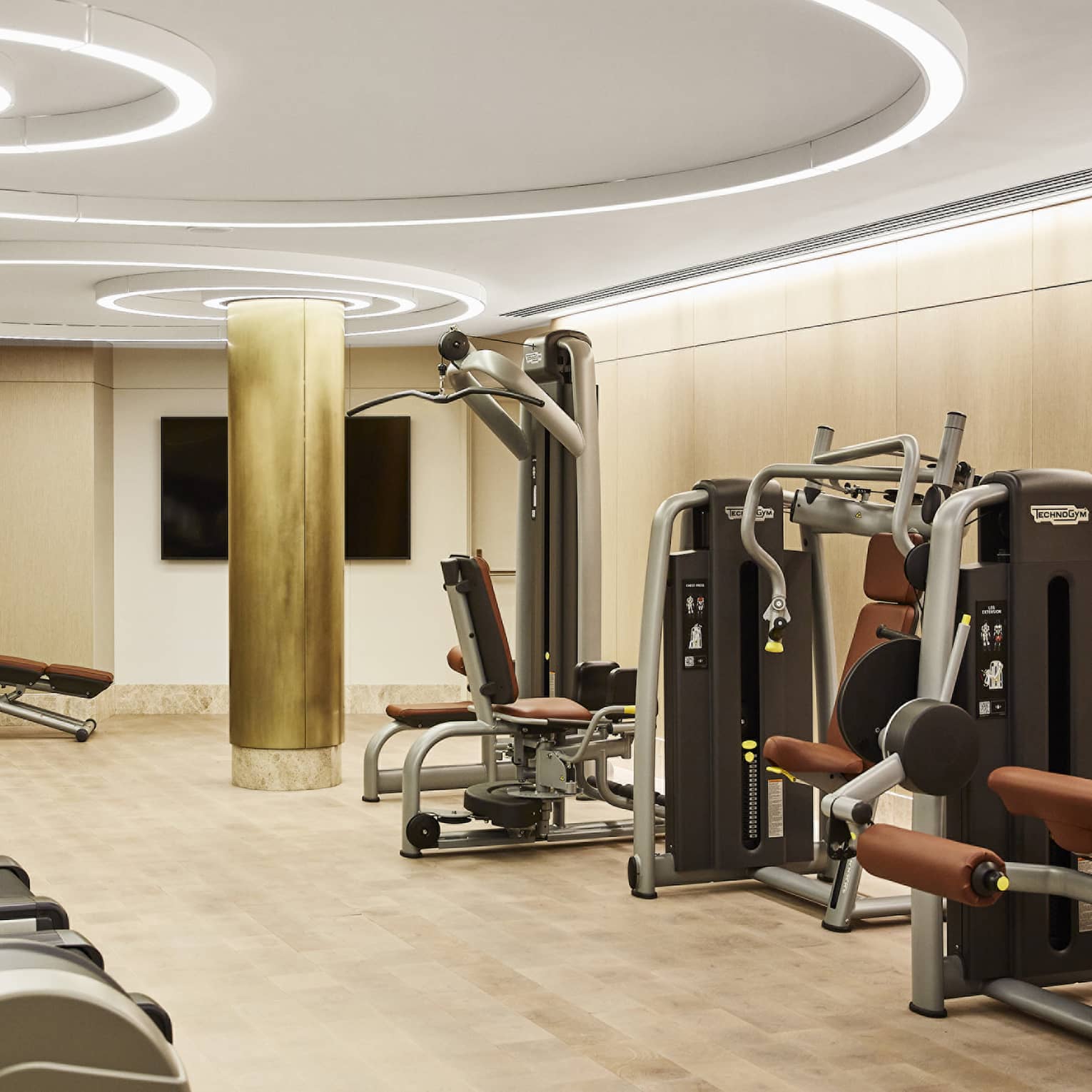 Fitness centre with three treadmills, weight-training machines, modern circular lights on the ceiling