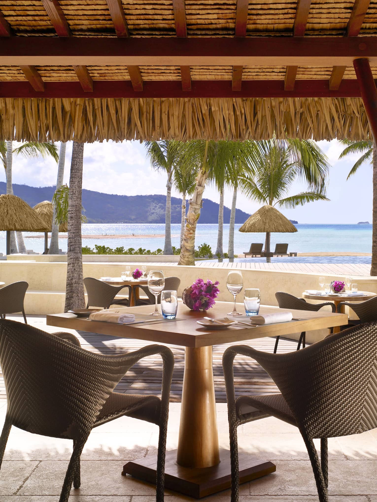 Tere Nui restaurant patio dining tables under flat thatched roof looking out at beach